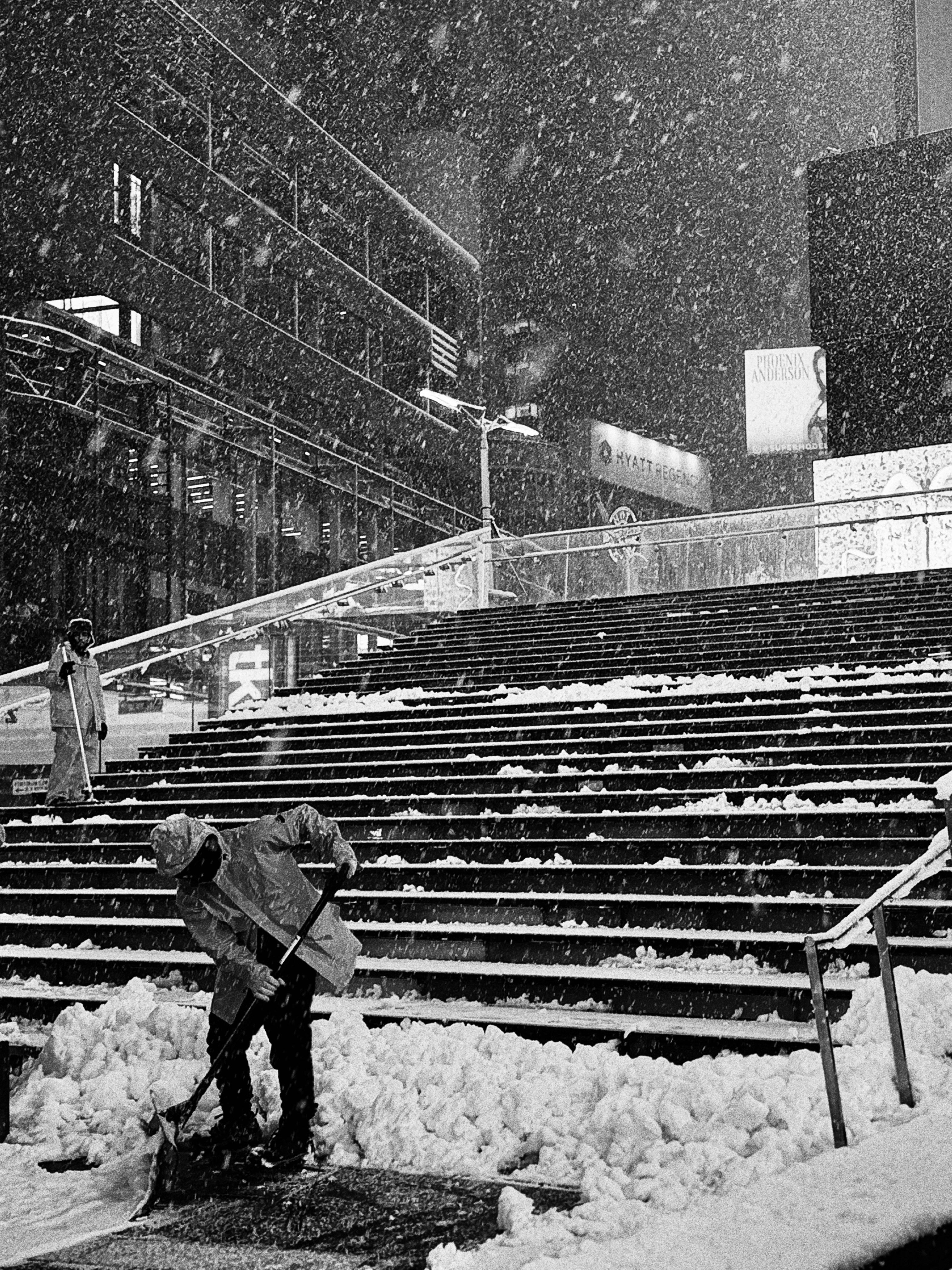 Man shoveling snow on city steps during snowfall