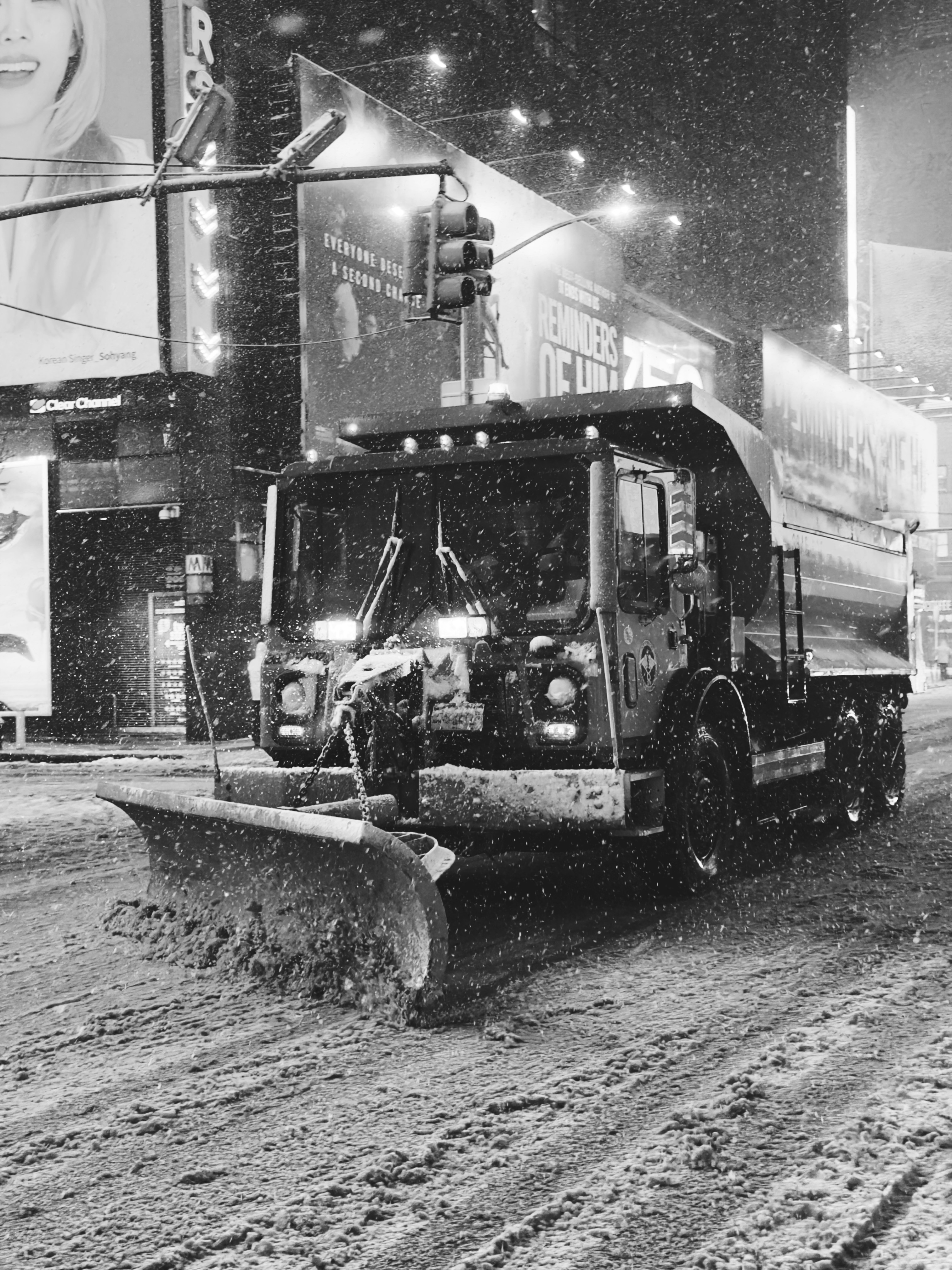 Snow plow clearing a city street at night