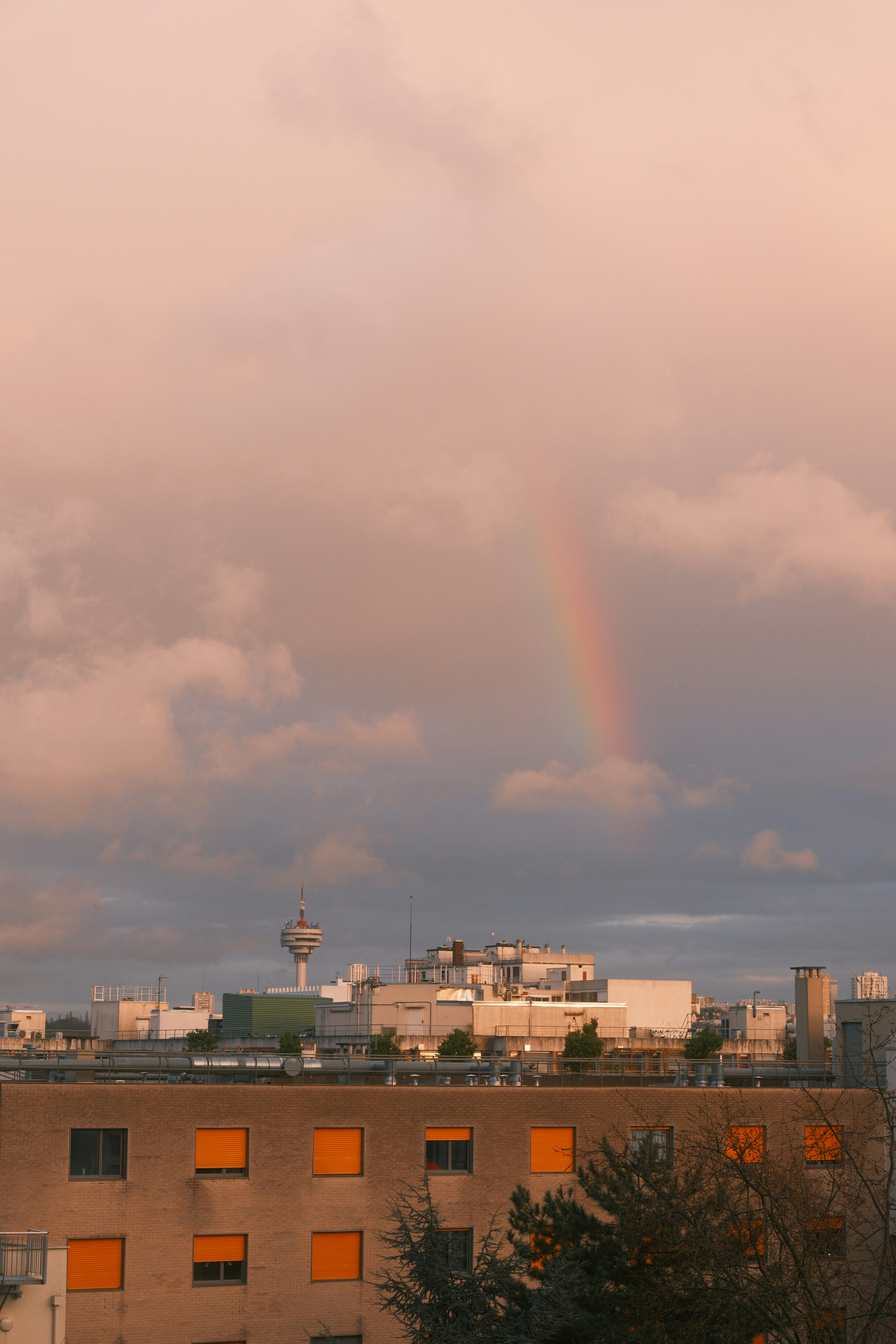 Rainbow over buildings during a cloudy sunset