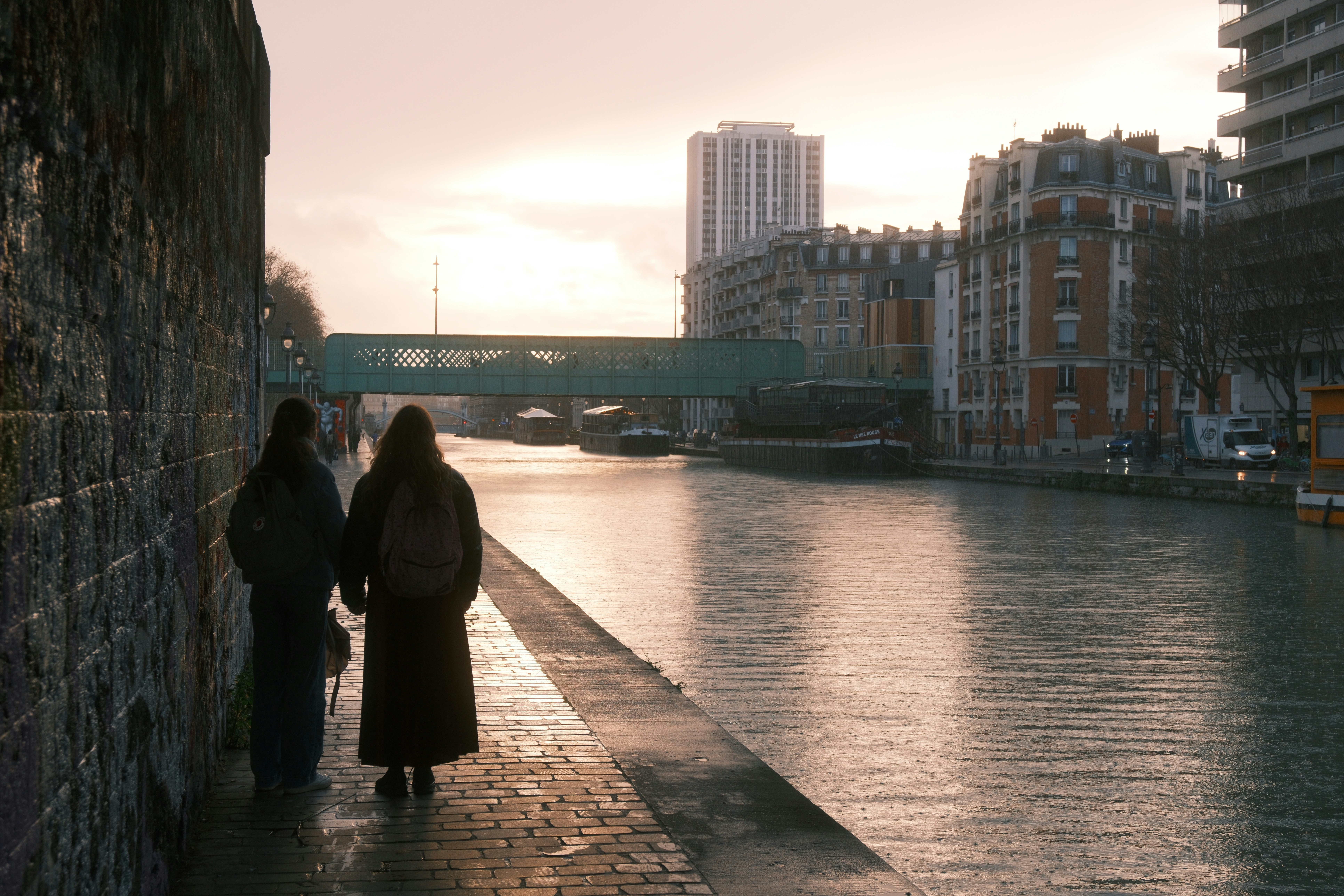 Two people walk along a canal at sunset