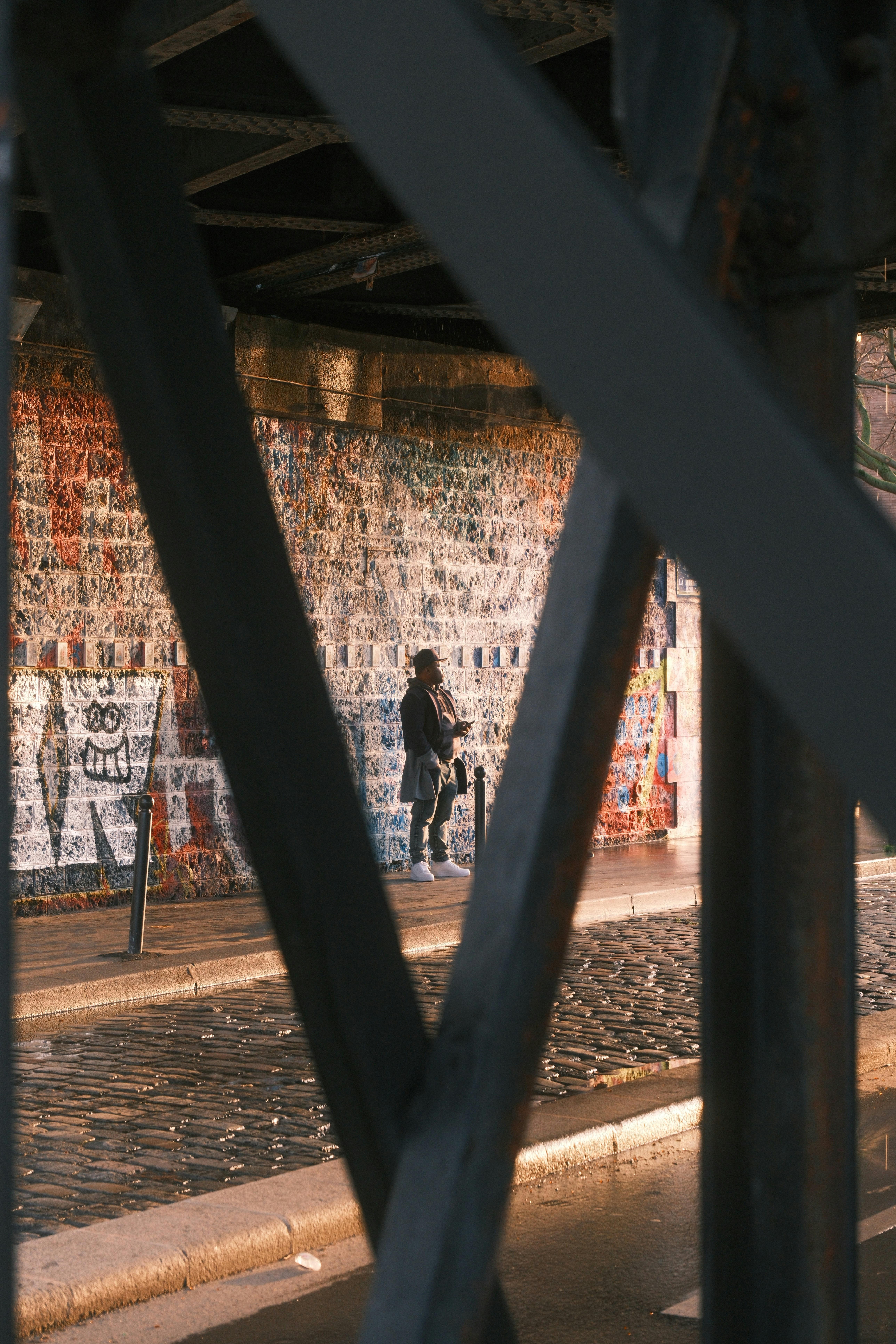 Person standing near graffiti wall under bridge