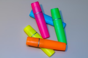 Several colorful highlighters scattered on a gray surface.