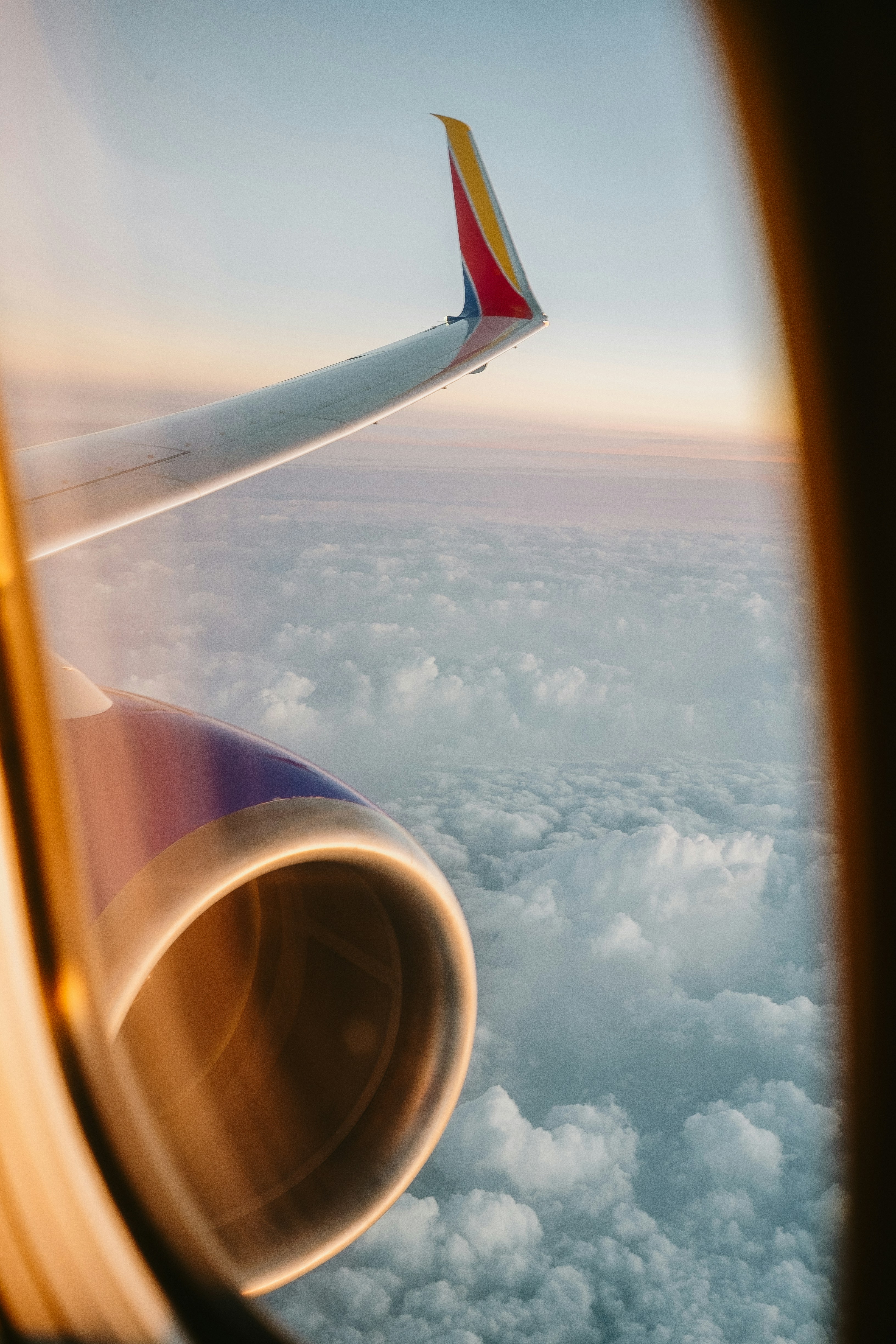 Moteur et aile d’avion au-dessus des nuages au coucher du soleil