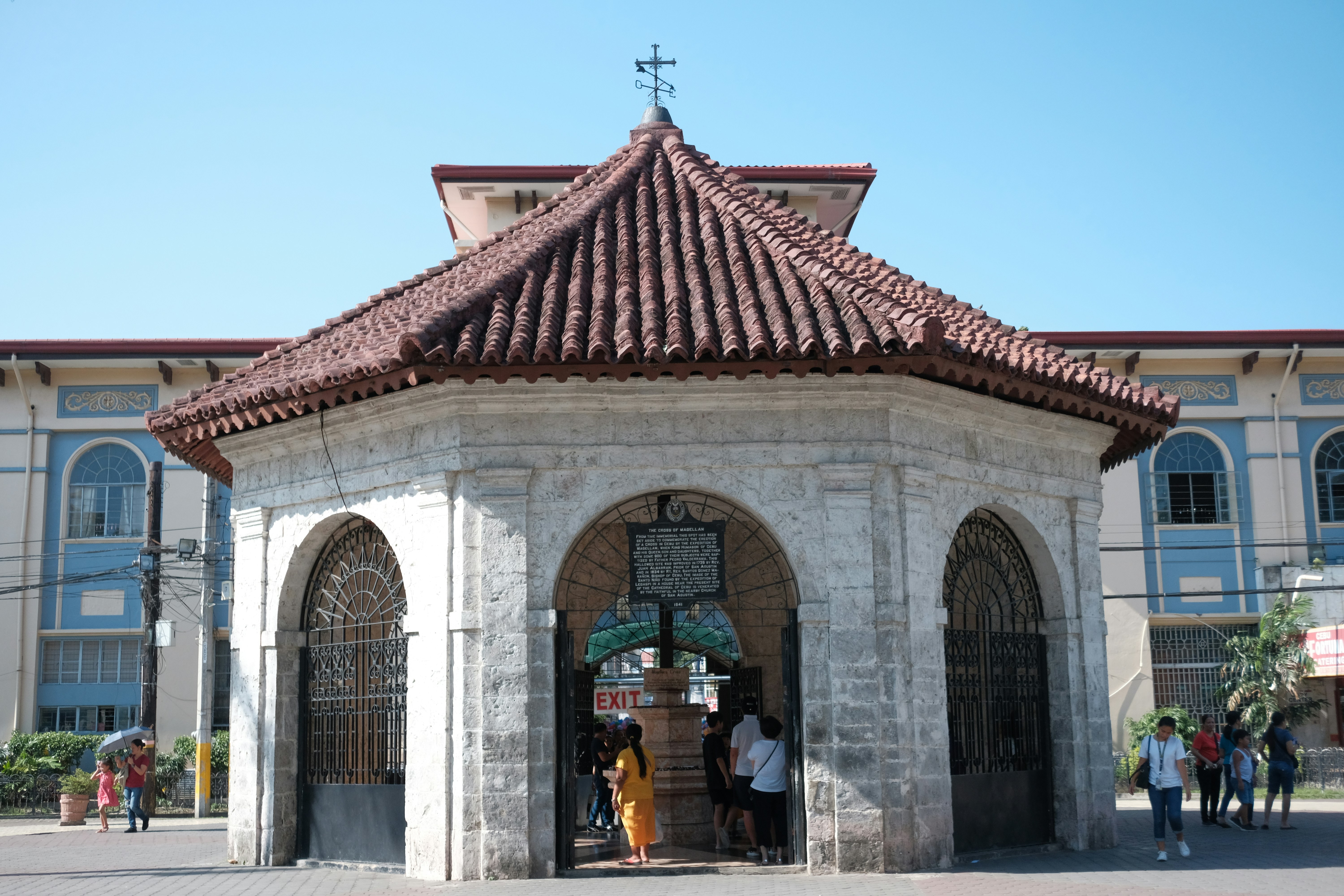 Historic stone structure with tiled roof and people