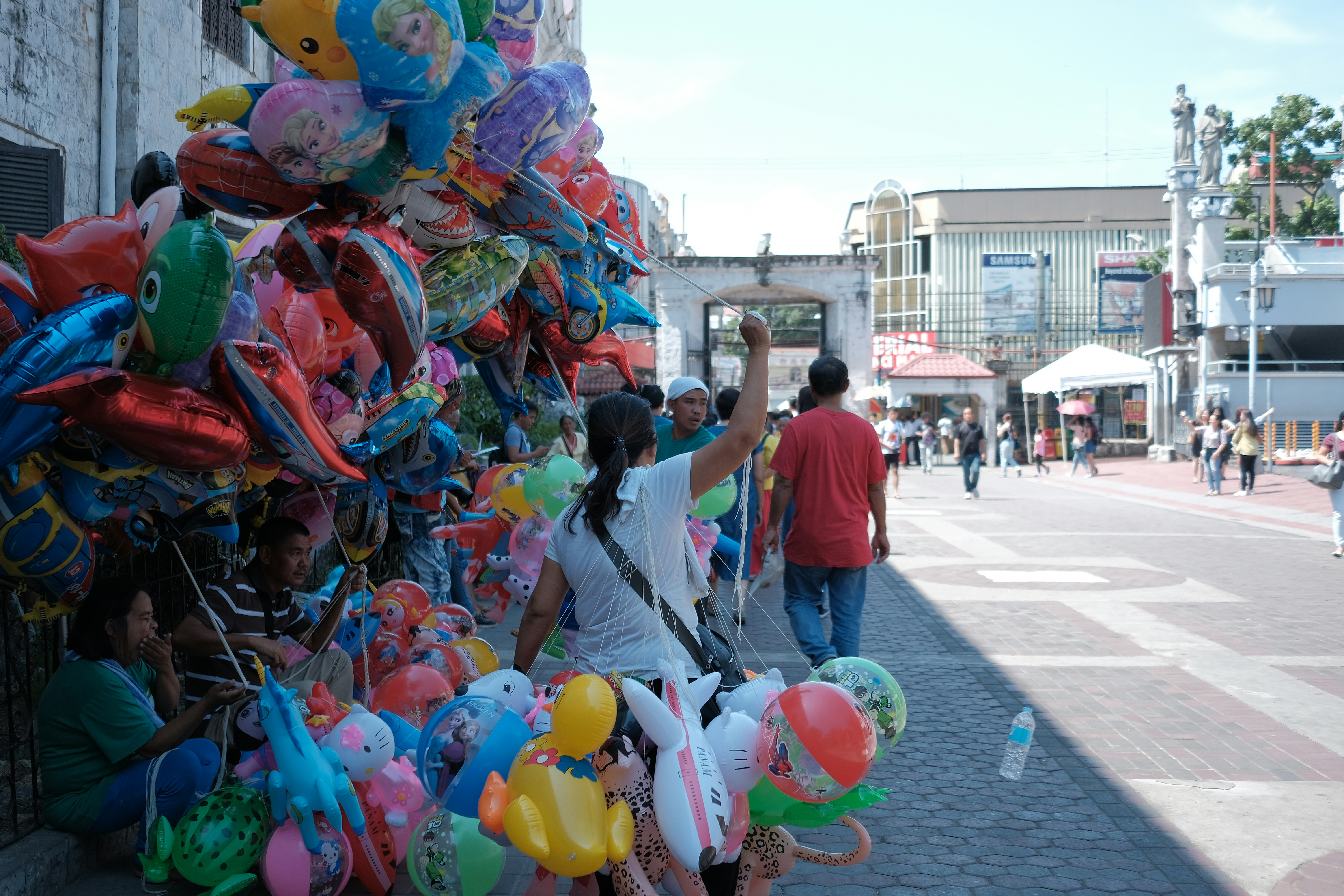 Street vendor selling colorful balloons on a sunny day.
