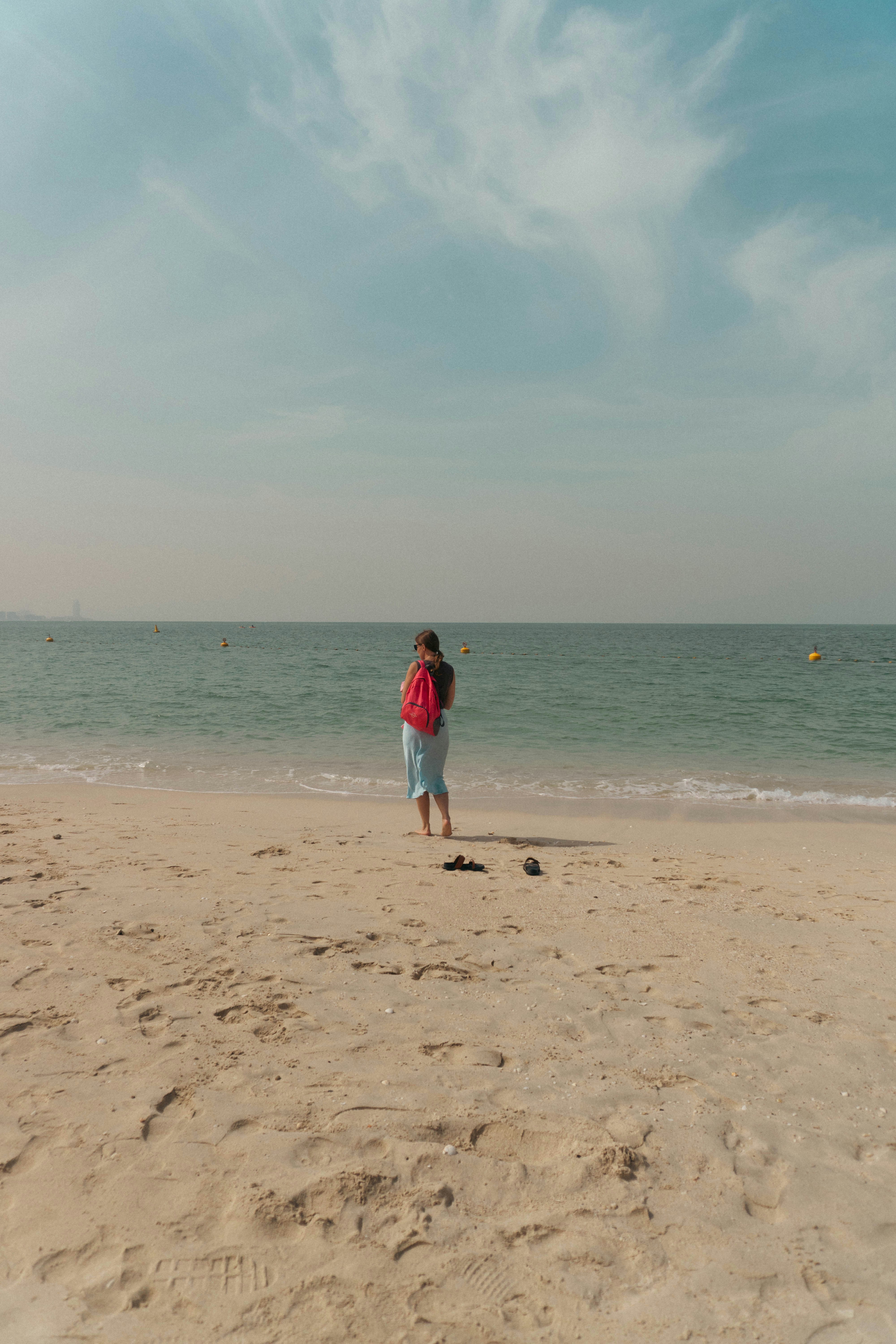 Eine Person steht an einem Sandstrand mit Blick auf den Ozean.