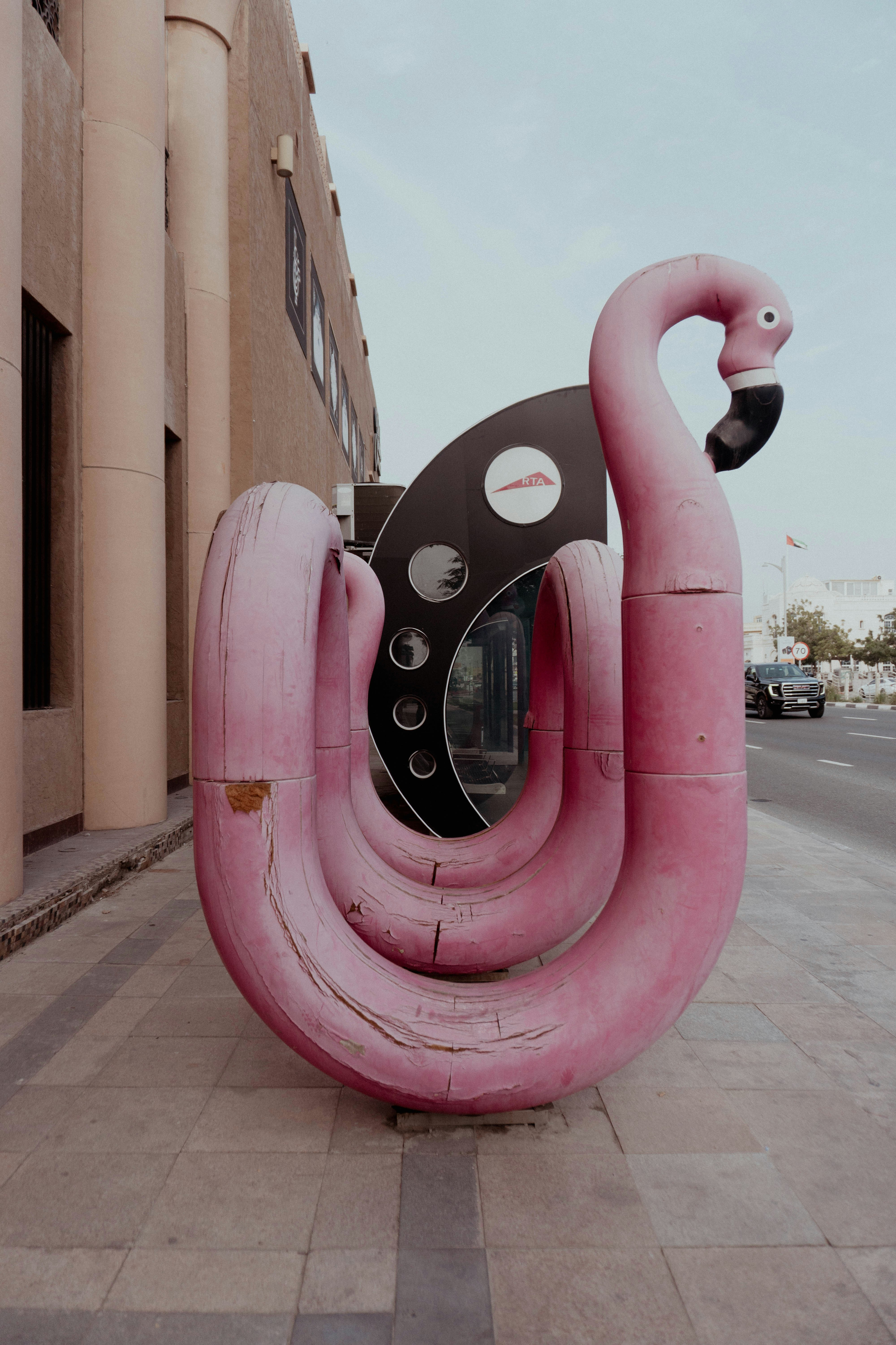 Eine große rosa Flamingo-Skulptur auf einem Bürgersteig.