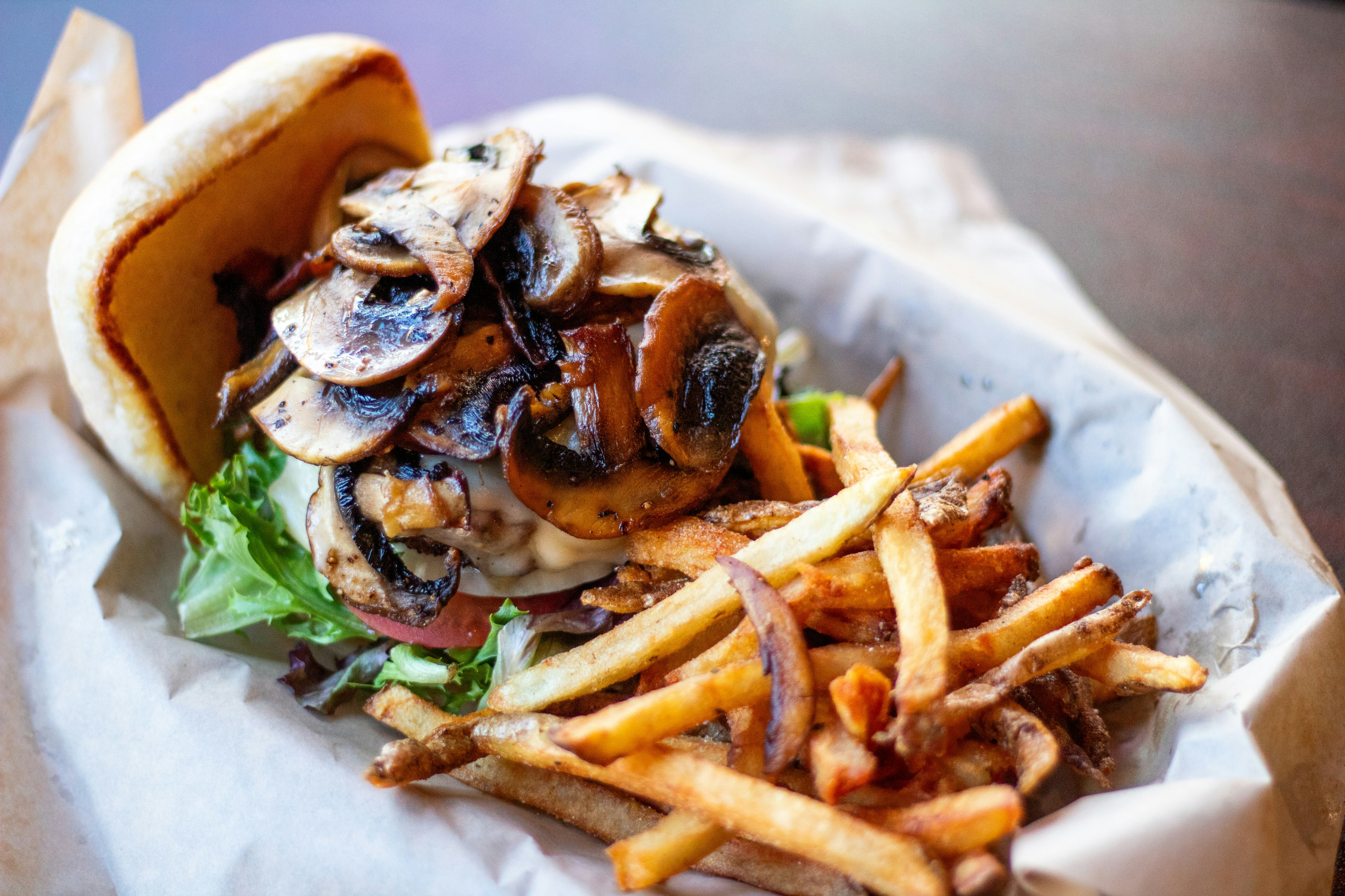 Burger with mushrooms and french fries served in basket