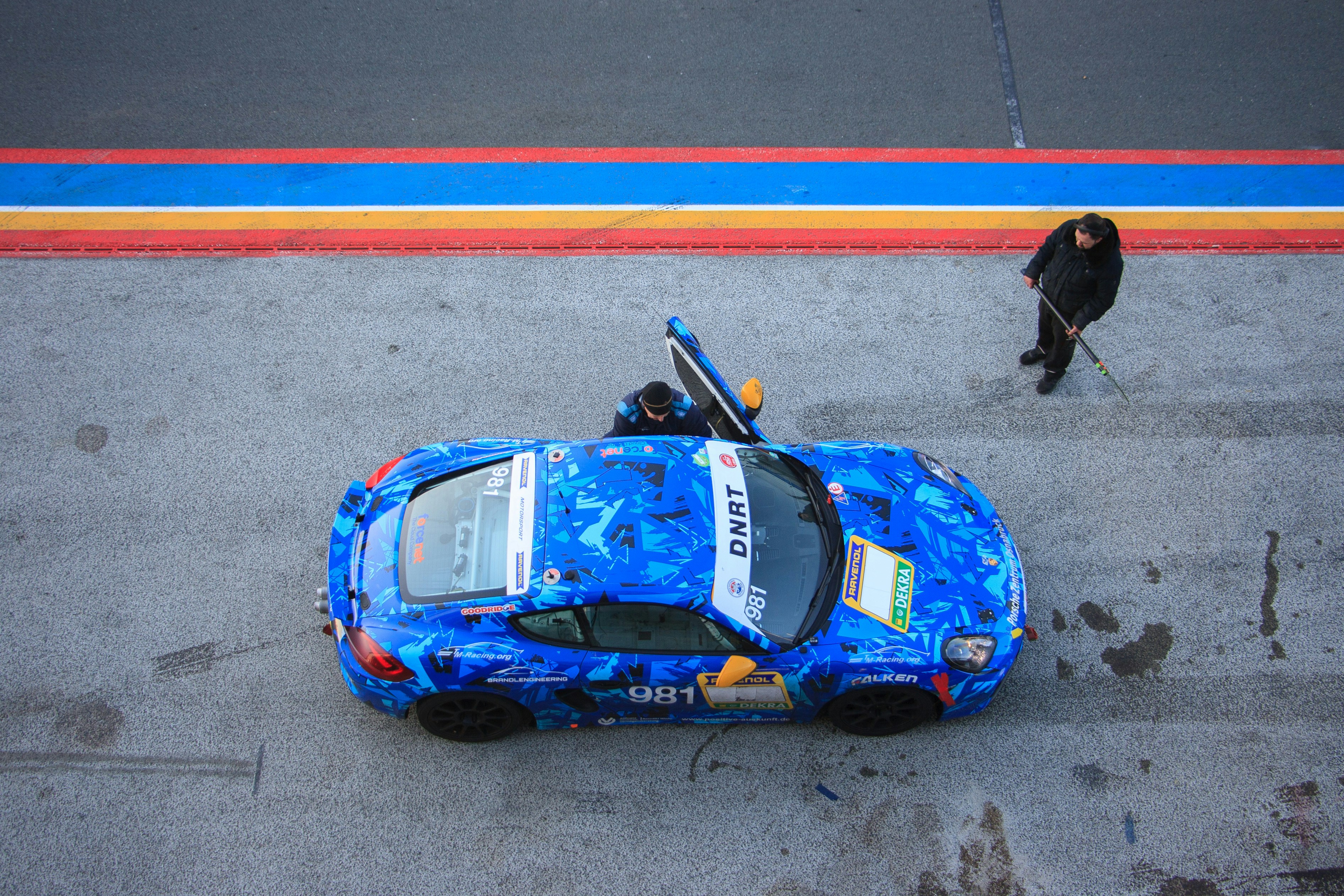 Blue race car with open doors on track