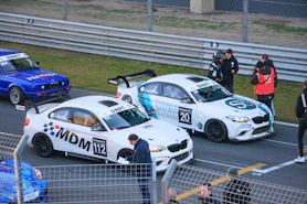 Race cars lined up on a track with drivers.