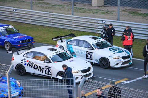 Race cars lined up on a track with drivers.