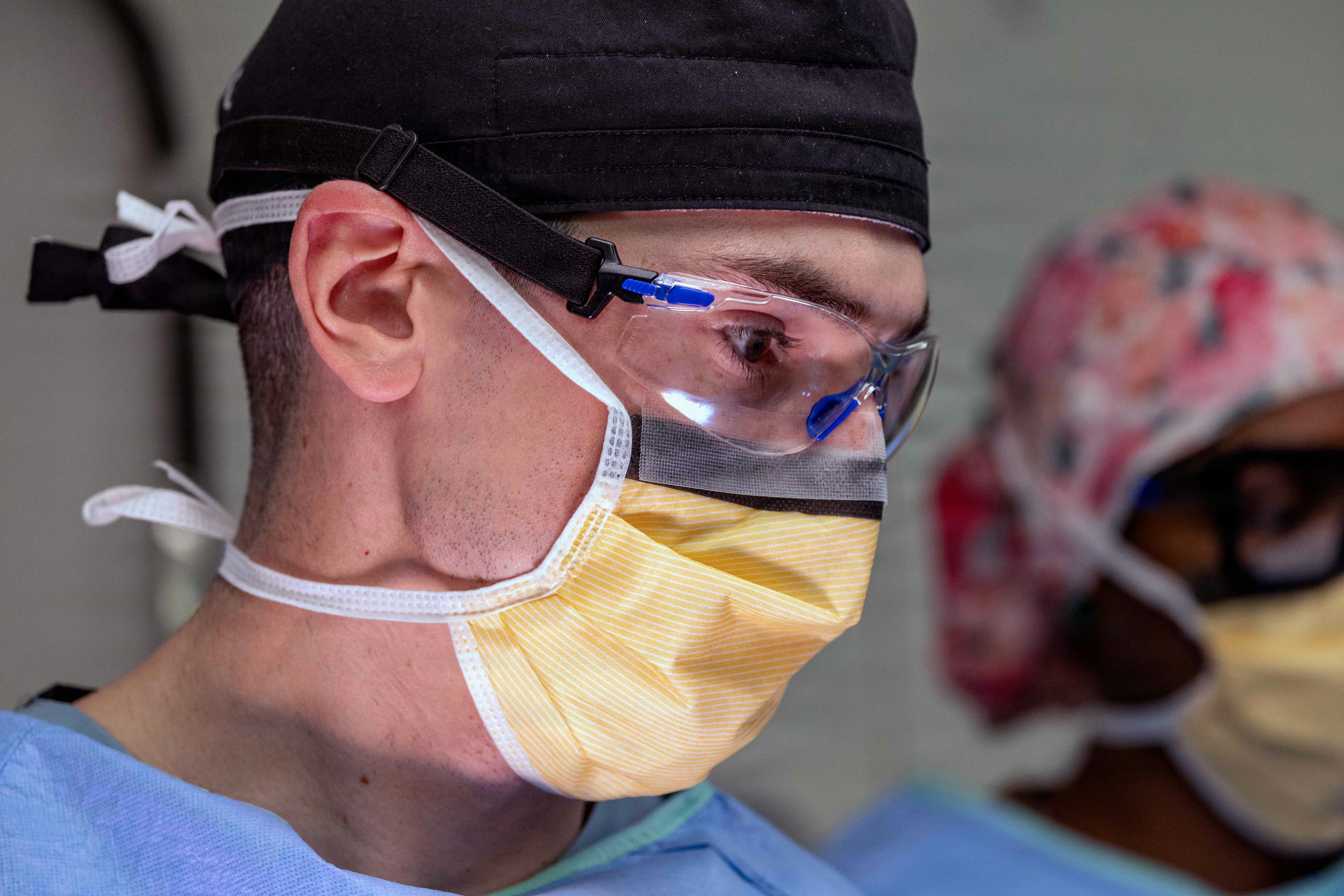Cirurgiões usando máscaras e equipamentos de proteção na sala de cirurgia.