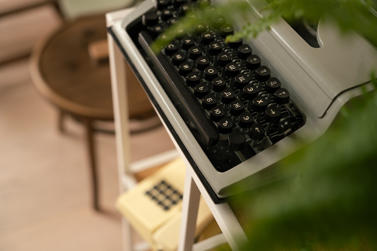 Vintage typewriter with black keys and green plant