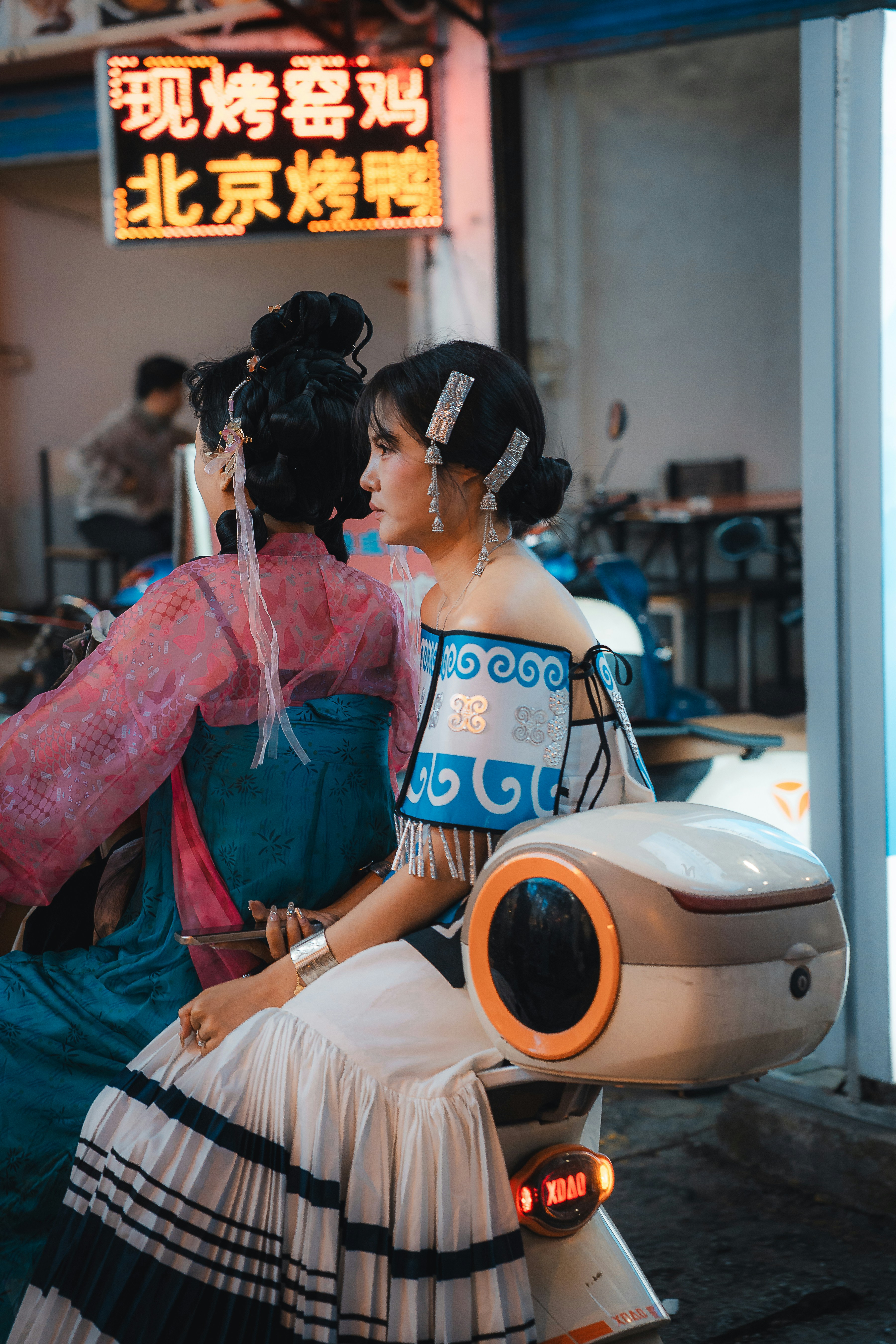 Dua wanita berpakaian tradisional Cina di atas skuter.