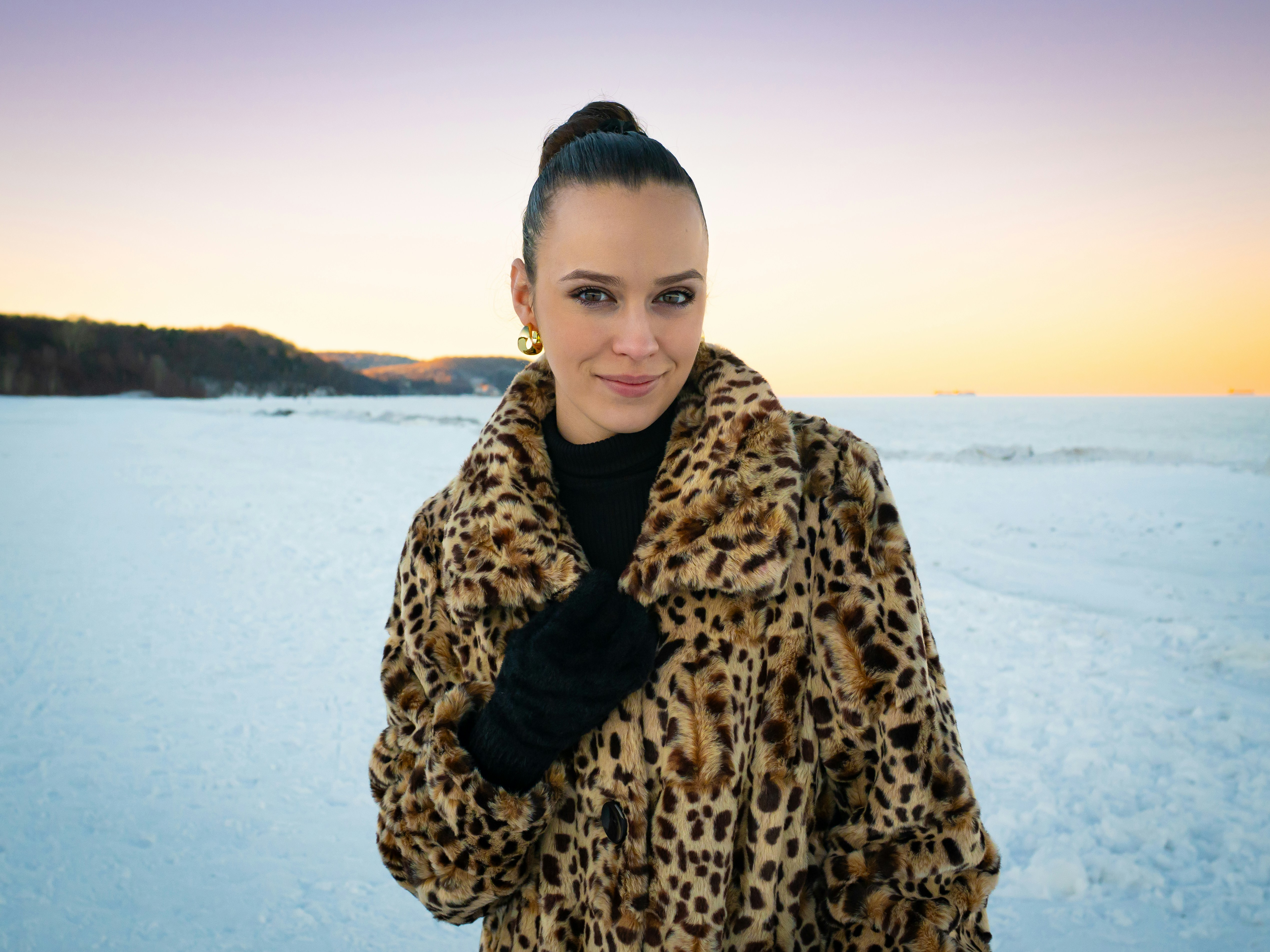 Femme en manteau léopard sur un paysage enneigé.