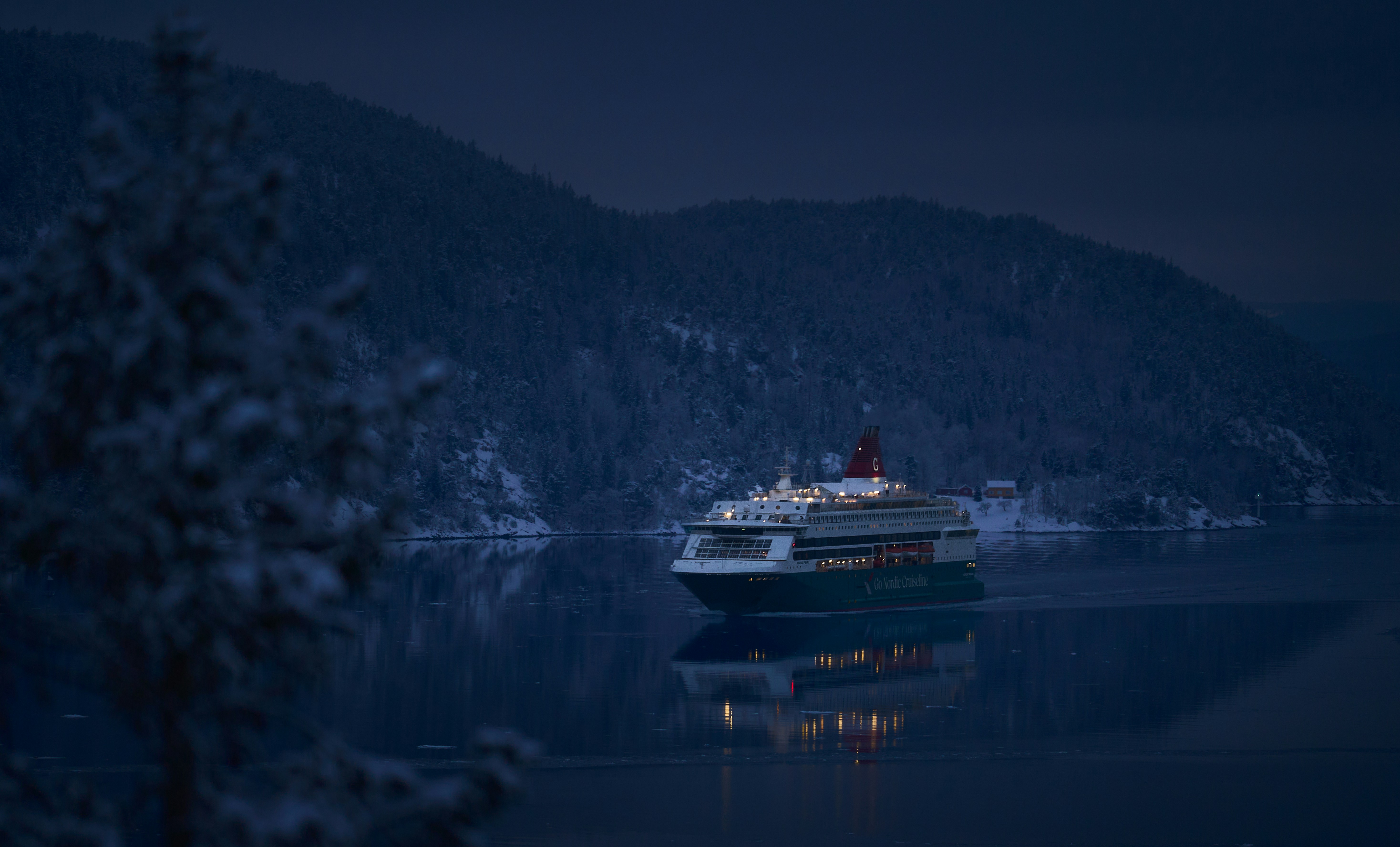 A large ship sails on a calm lake at dusk.