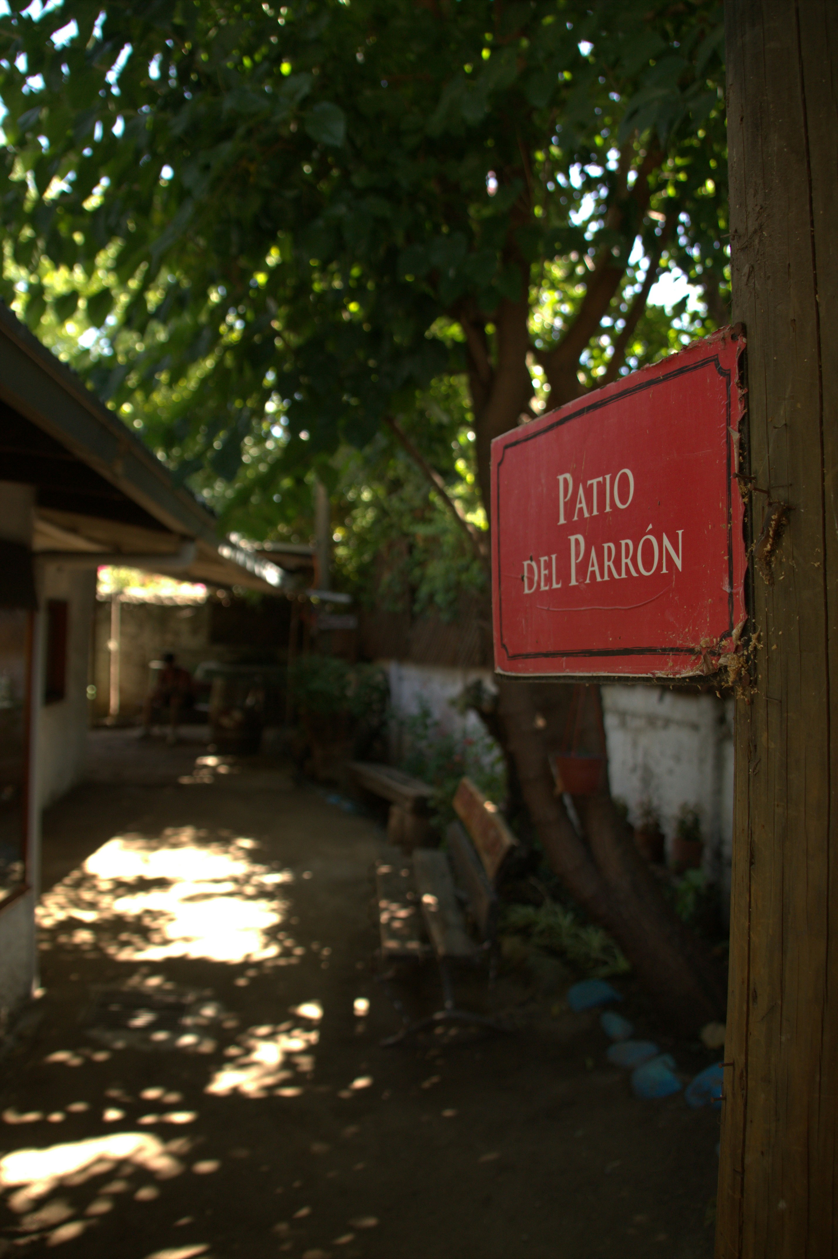 Un panneau rouge porte l’inscription patio del parrón dans une cour.