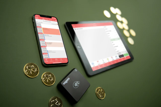 A tablet, phone, card reader and coins on a surface representing digital payment systems