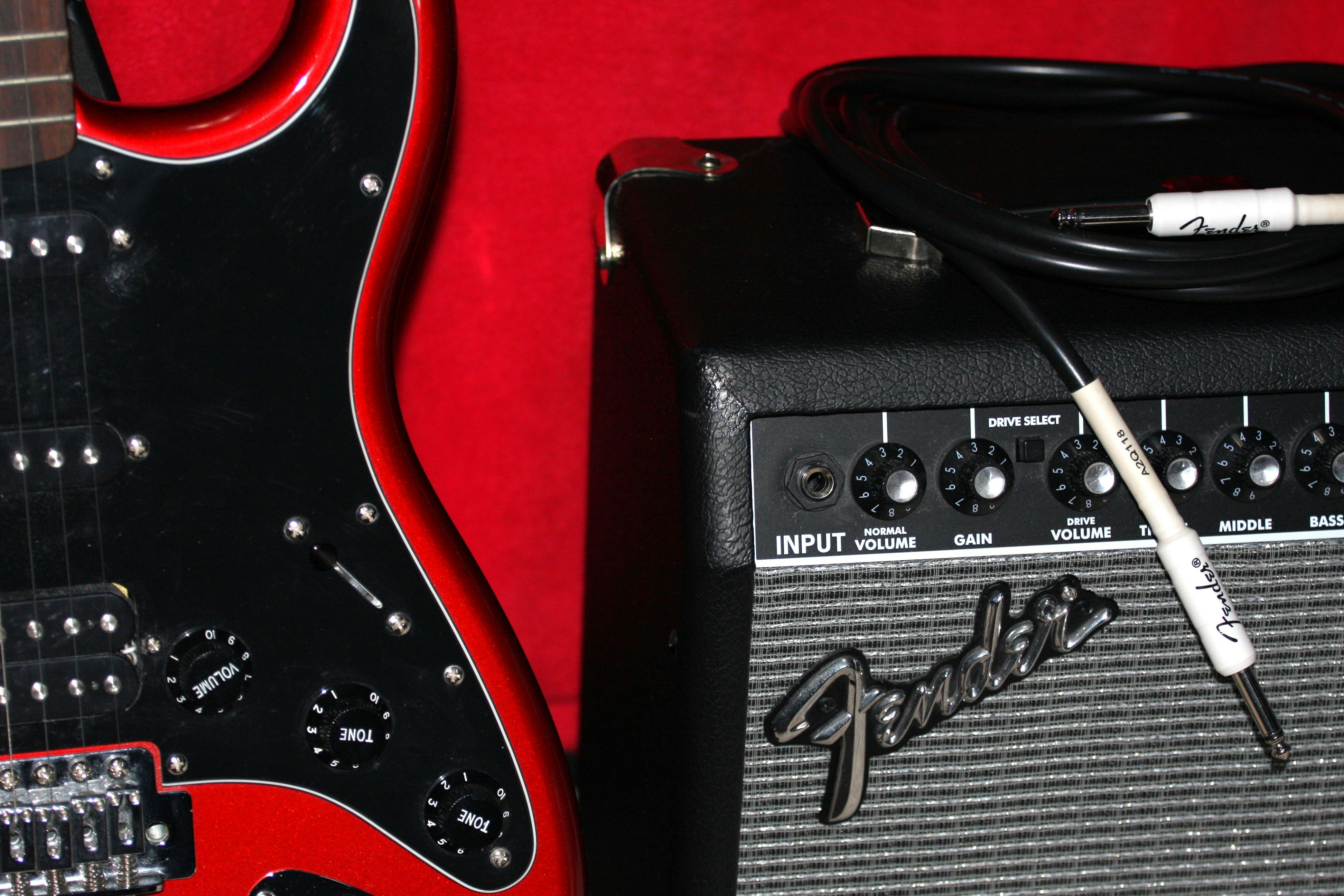 Black electric guitar with red trim next to amplifier