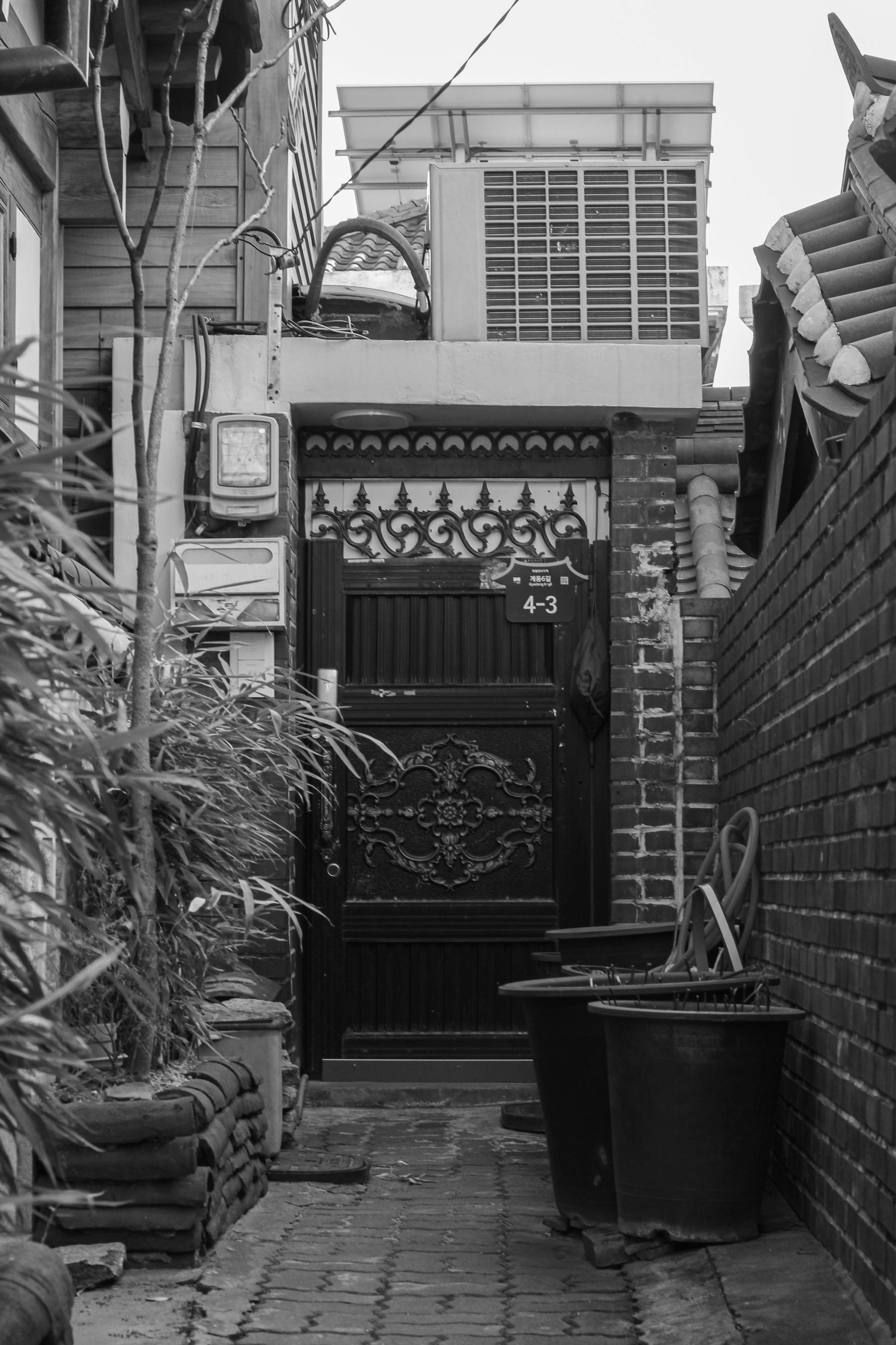 Narrow alleyway with a decorative door and air conditioner.