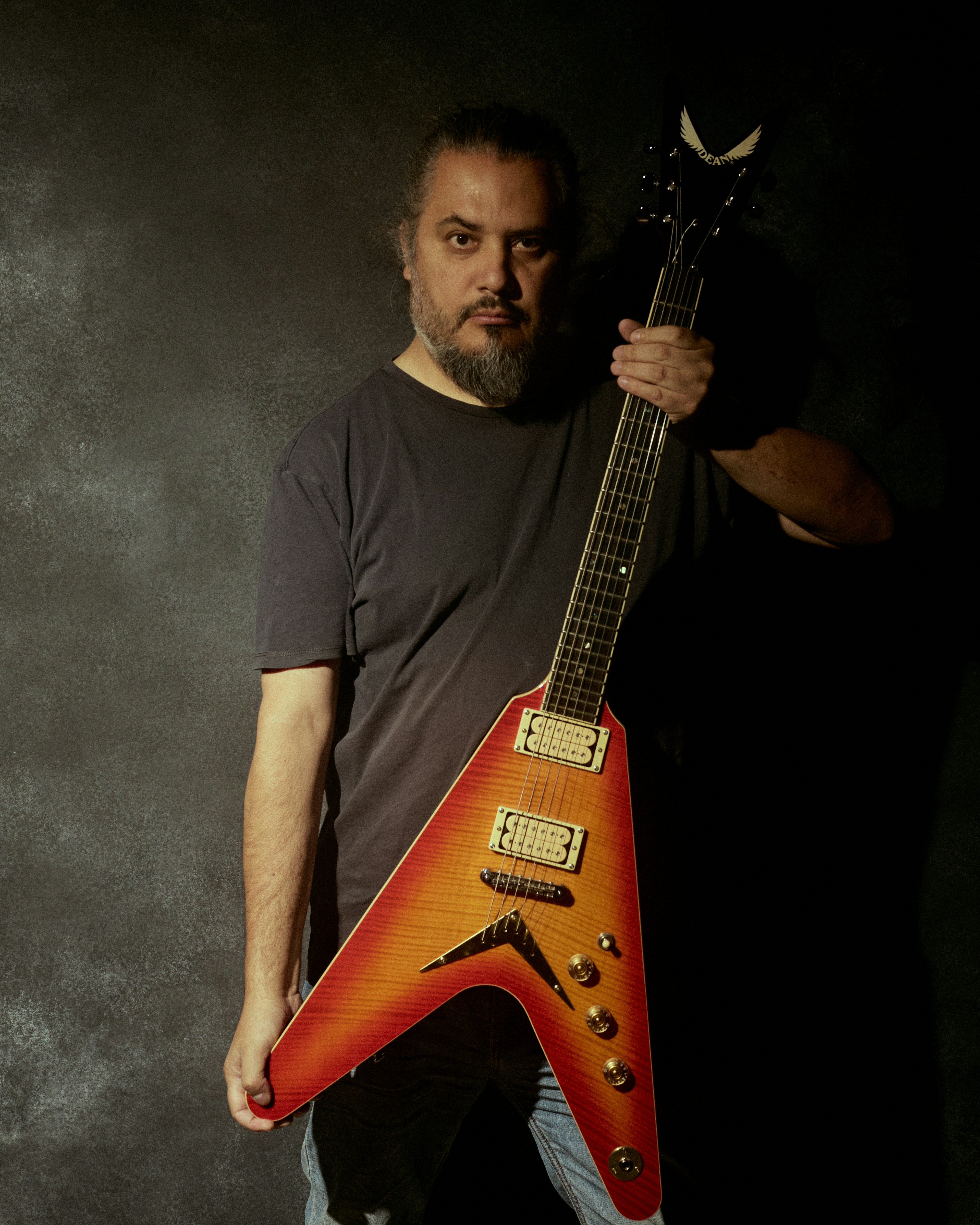Man holding a v-shaped electric guitar