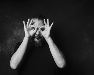 Man with beard making circle gesture over eyes