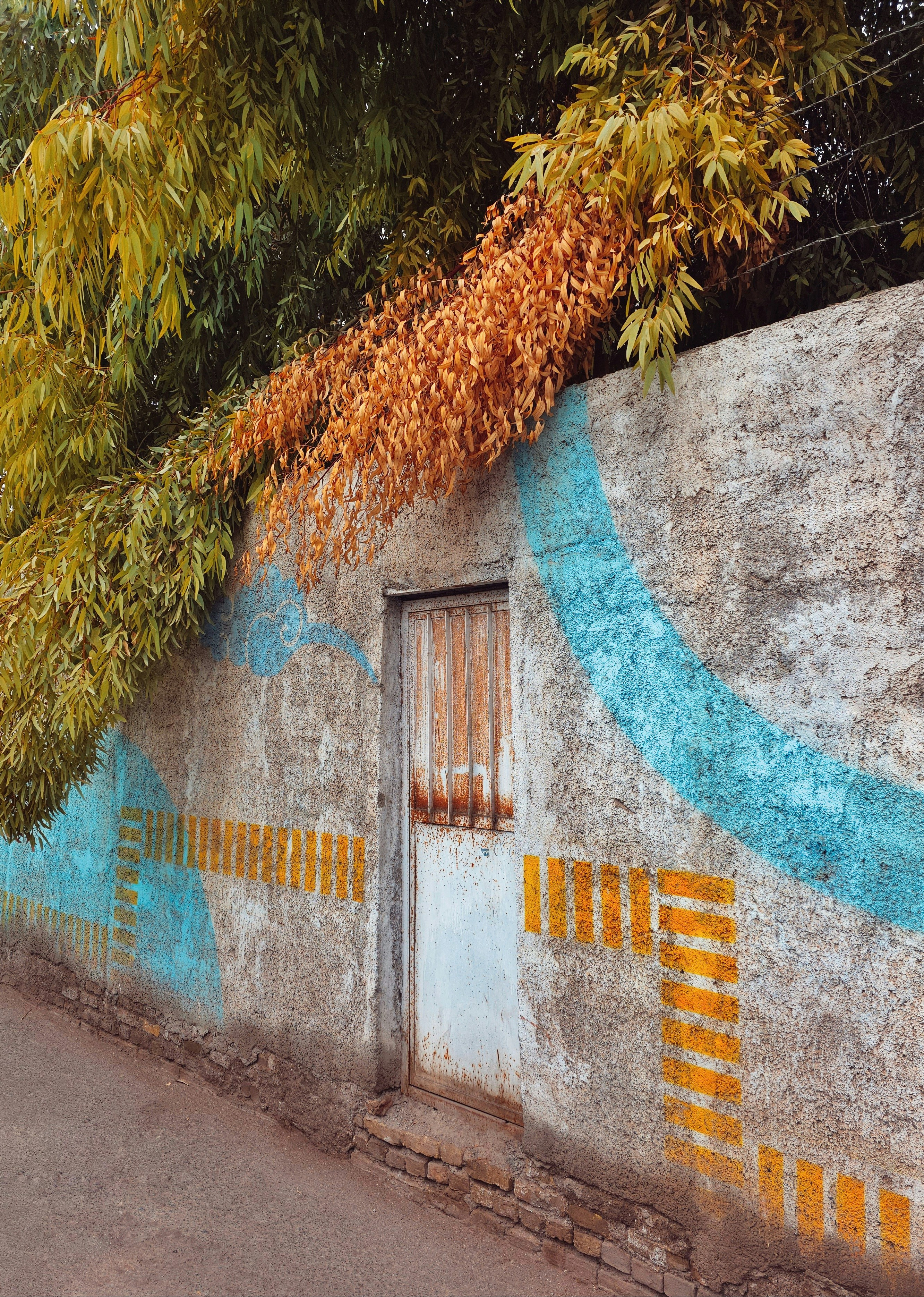 A weathered wall with blue and yellow abstract art.