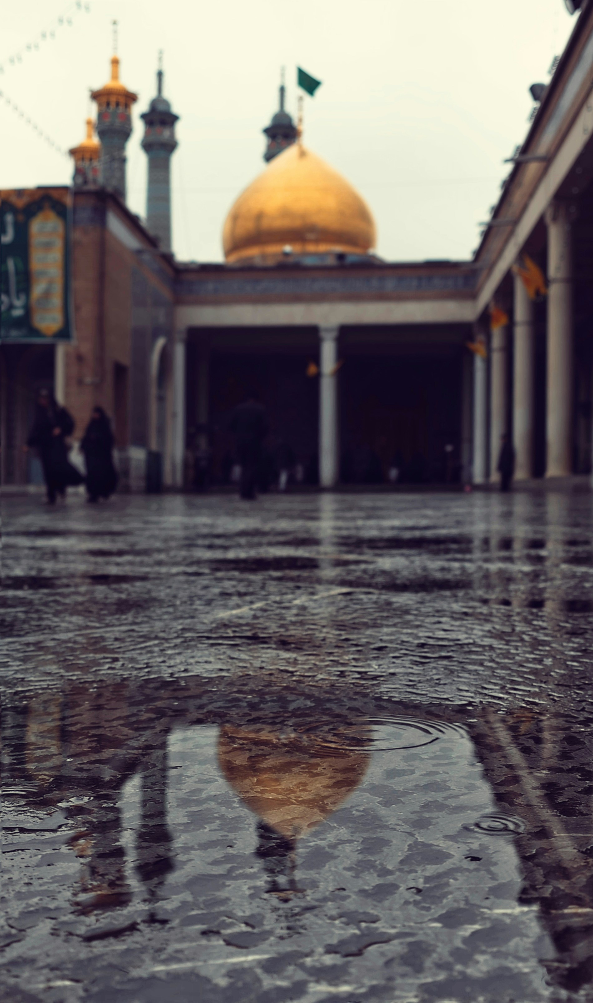 Golden dome reflected in wet courtyard pavement