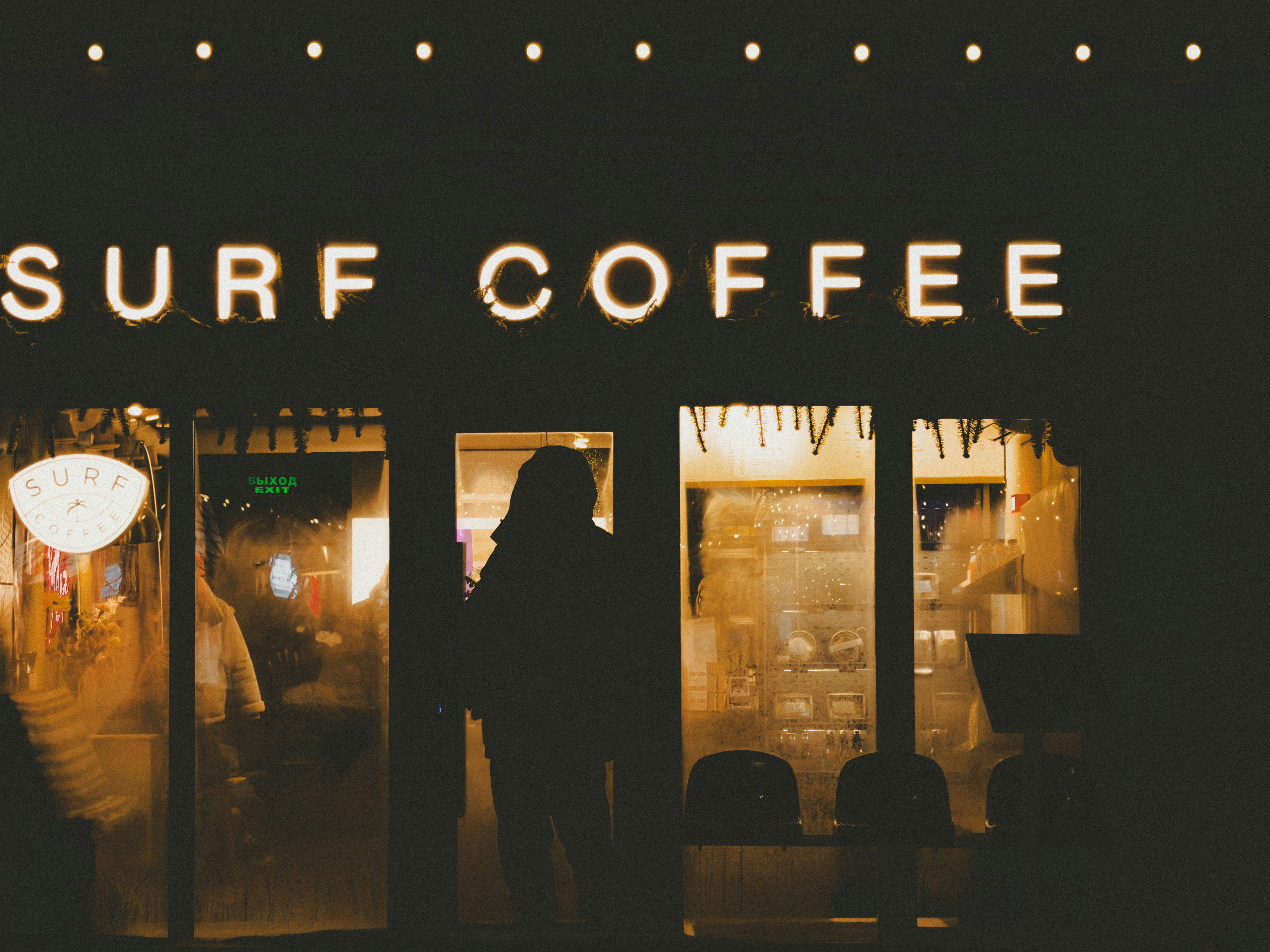 Person silhouetted in a doorway of surf coffee at night.