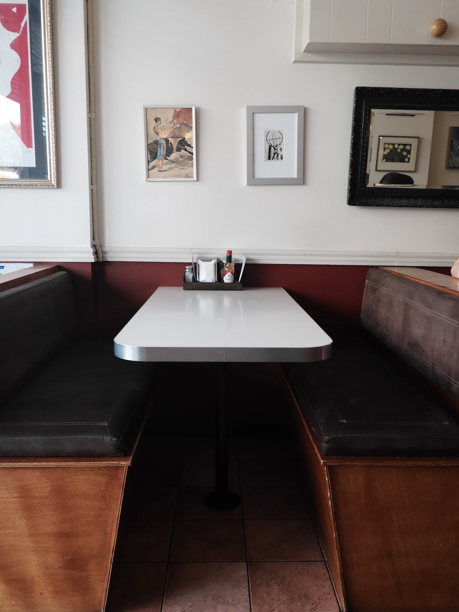 A corner booth with a bare table and a condiment caddy