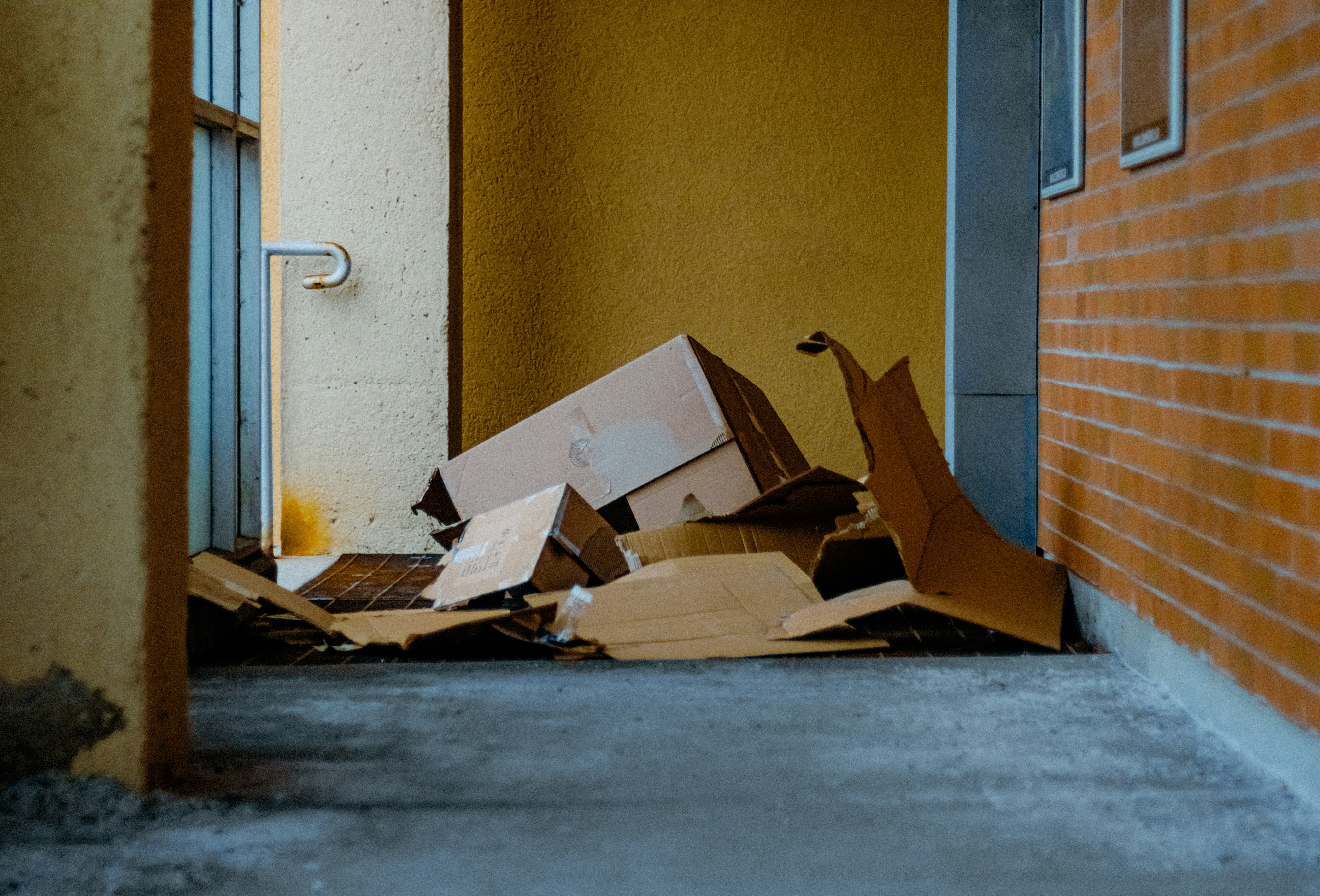 Cardboard boxes piled up outside a building entrance.