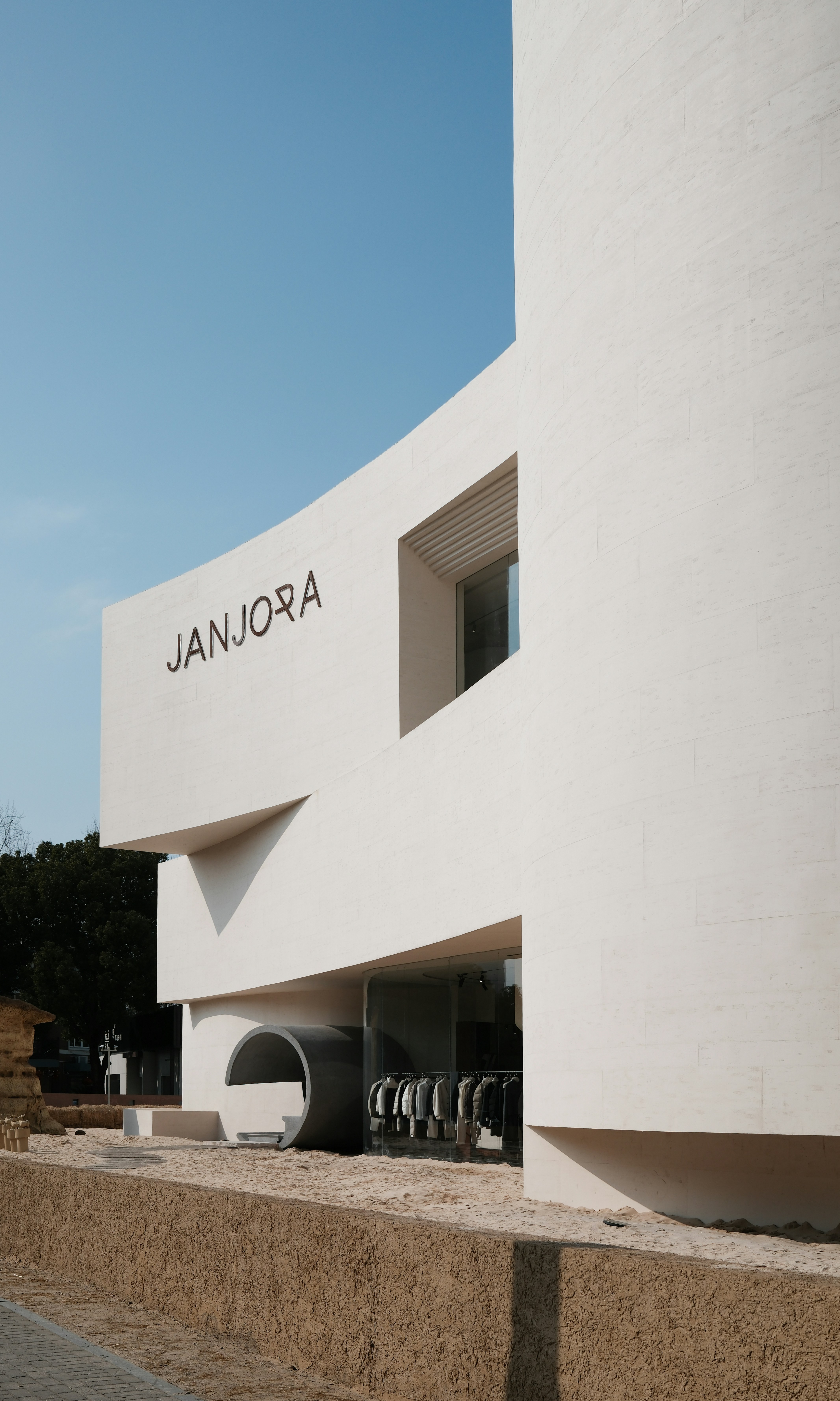 Edificio moderno blanco con fachada curva y cartel.