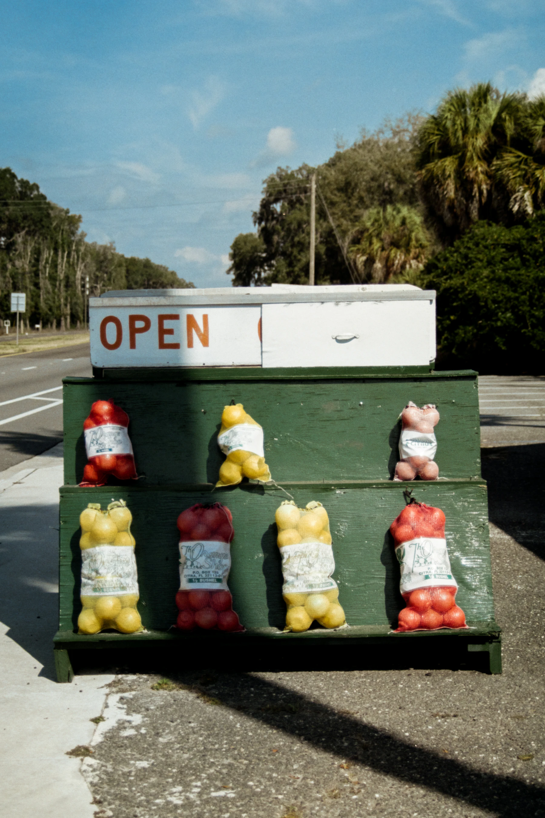 Produce stand with bags of onions and tomatoes