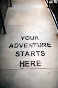 Your adventure starts here painted on sidewalk