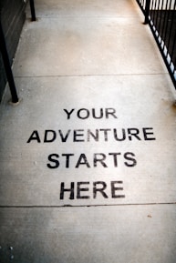 Your adventure starts here painted on sidewalk.