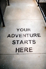 Your adventure starts here painted on sidewalk.