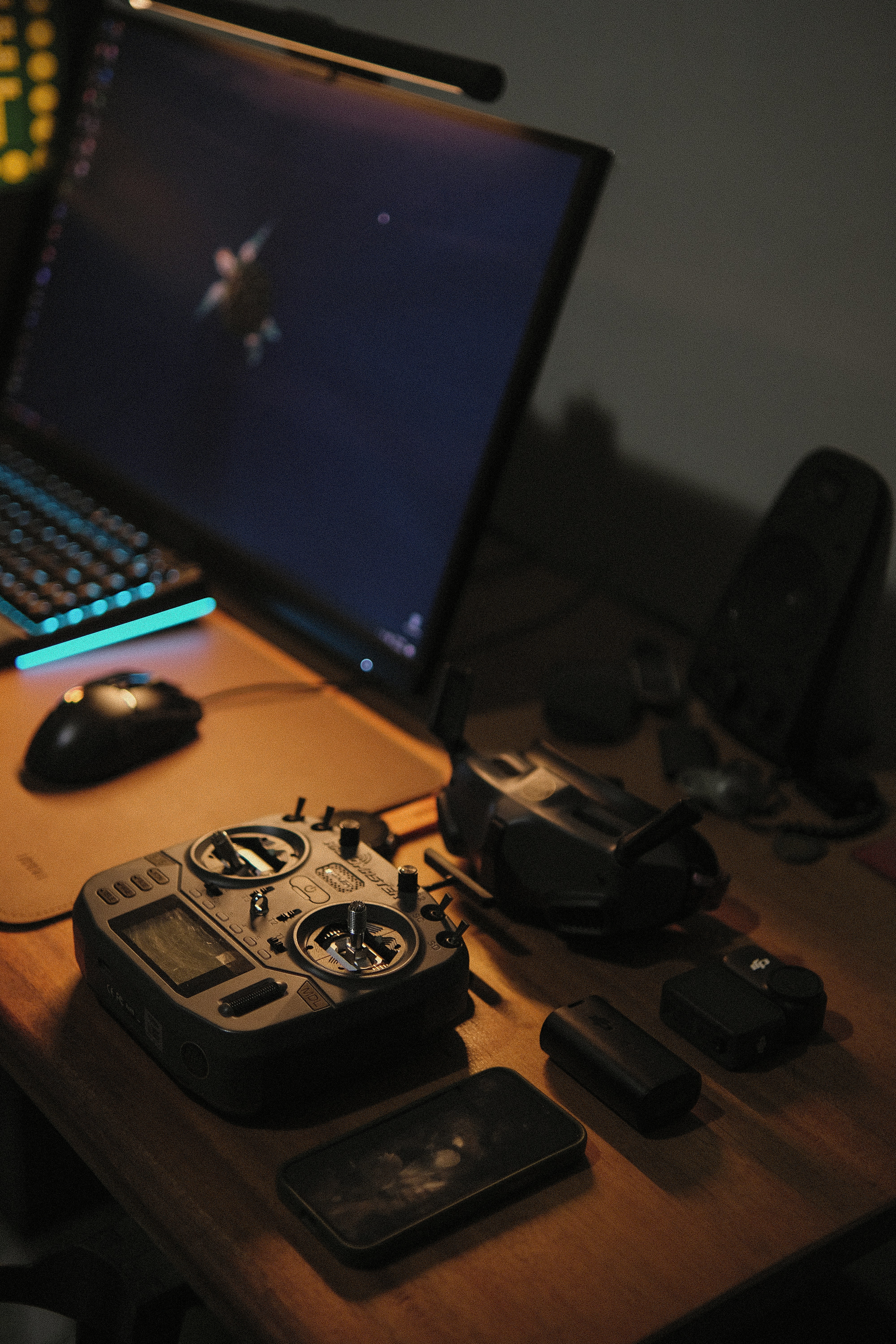 Remote control, drone, and laptop on a wooden desk.