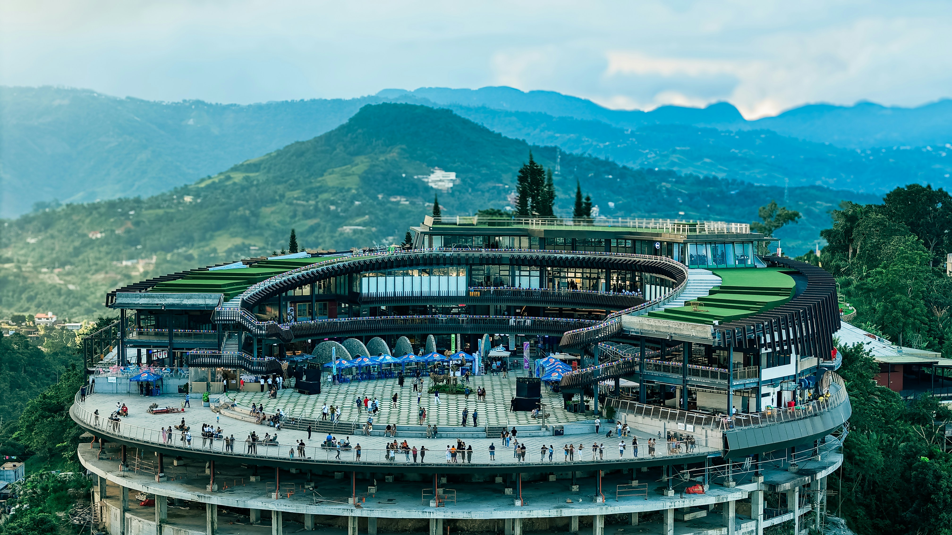 Modern circular building on a lush green hillside.