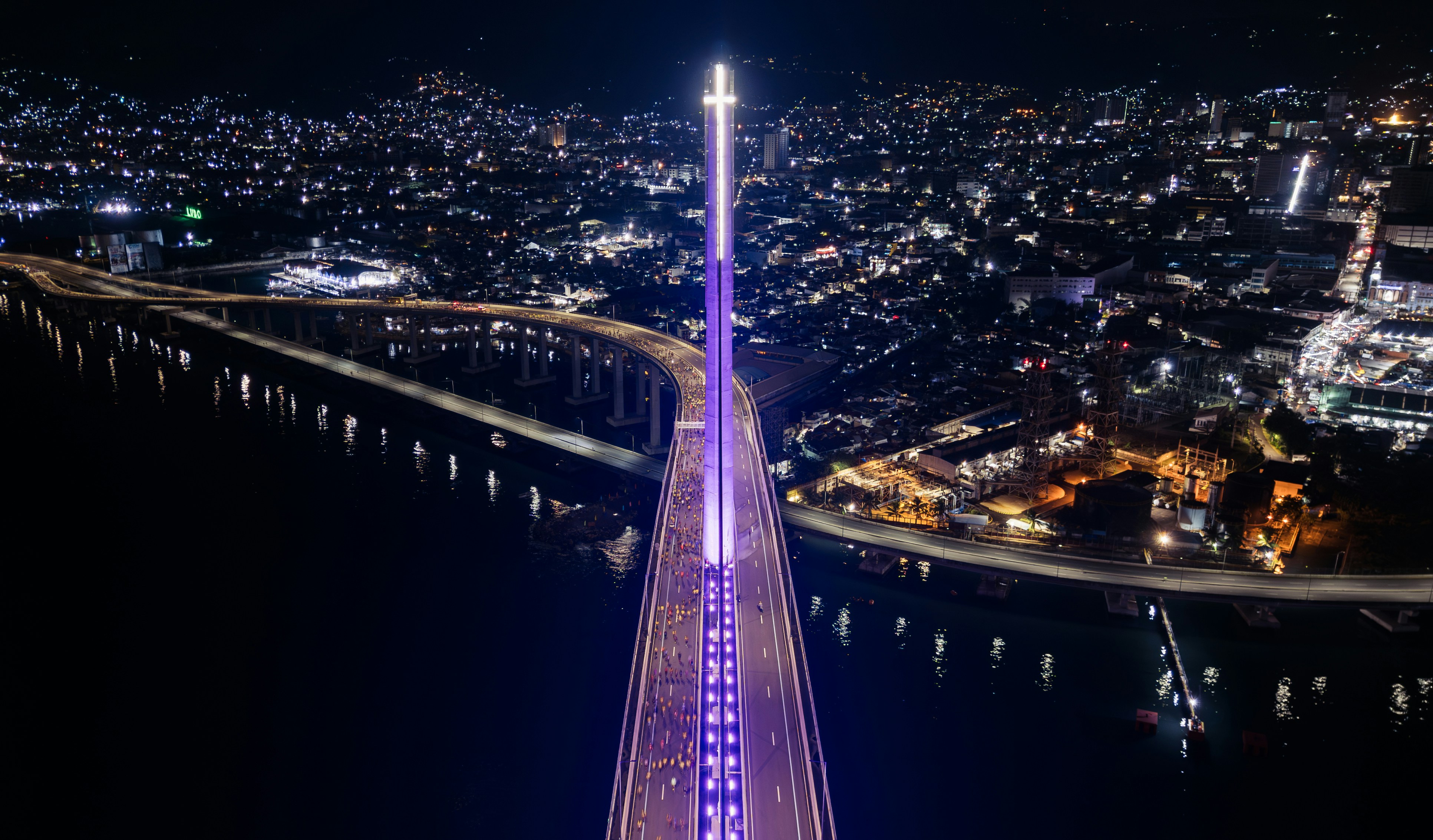 Illuminated bridge at night with city lights in background