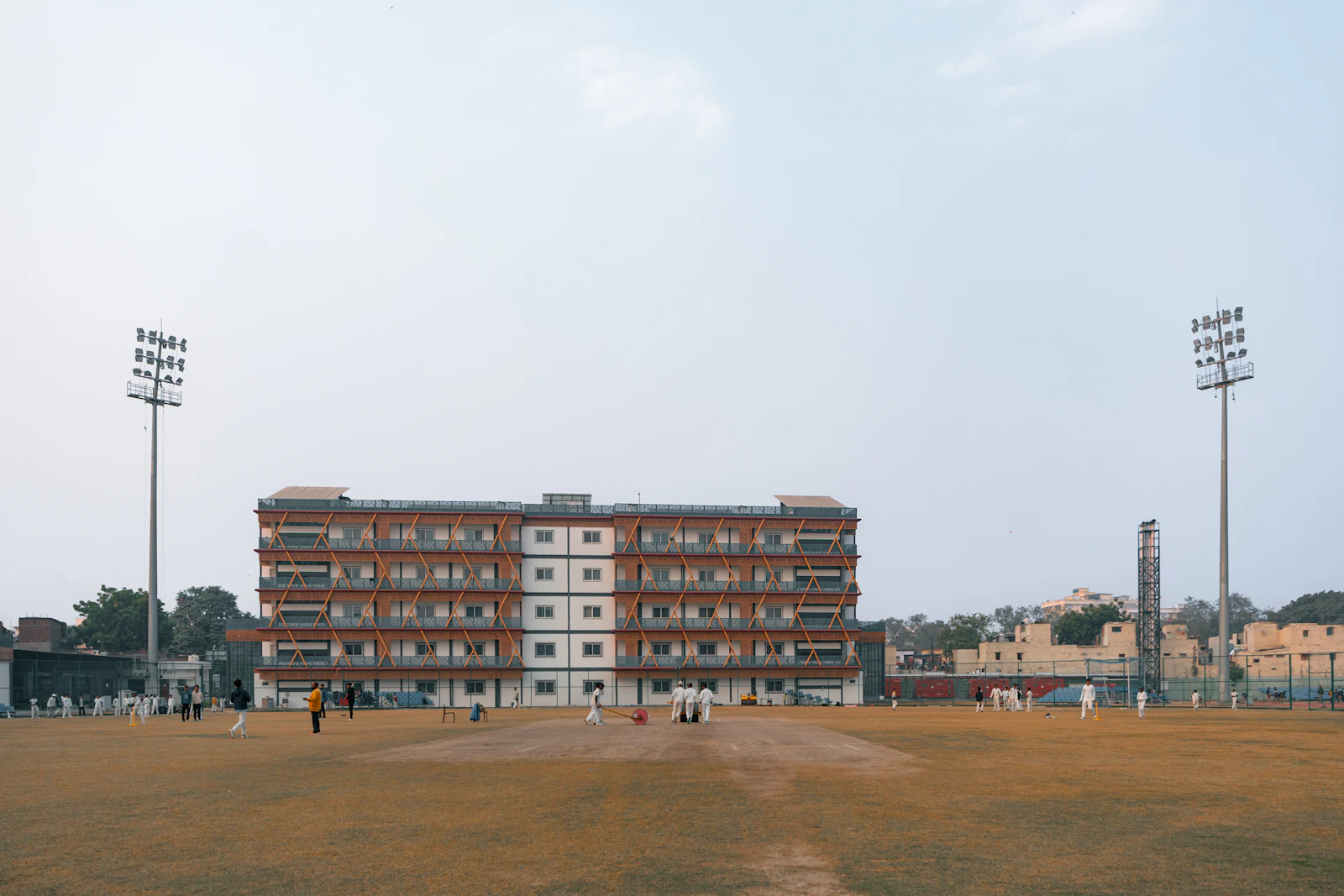 Cricket field with floodlight towers beside a building