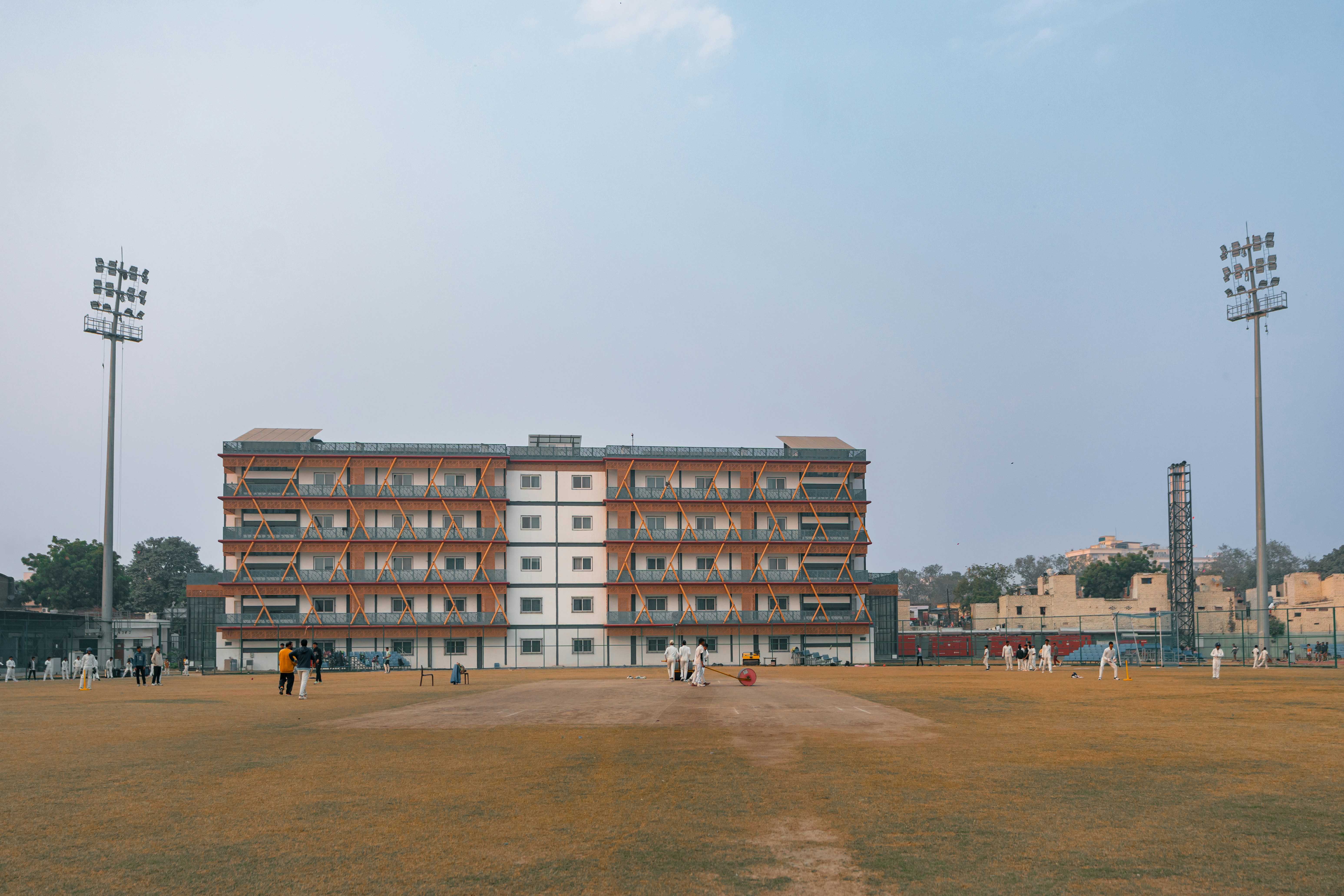 Cricket field with a large brick building and stadium lights
