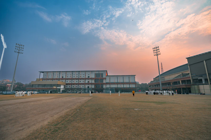 Cricket stadium under floodlights at sunset