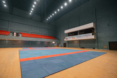 Indoor stadium with a blue and orange wrestling mat.