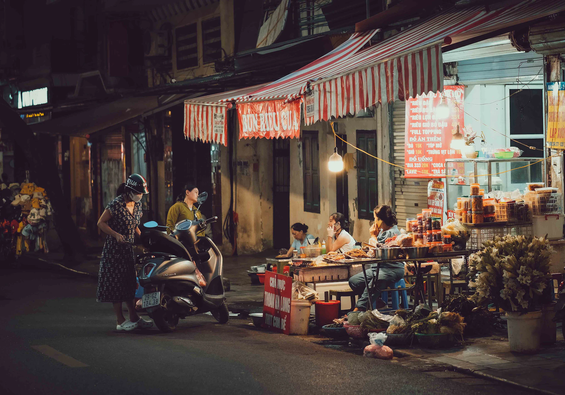 People eating at a street-food stall at night in Hanoi, Vietnam