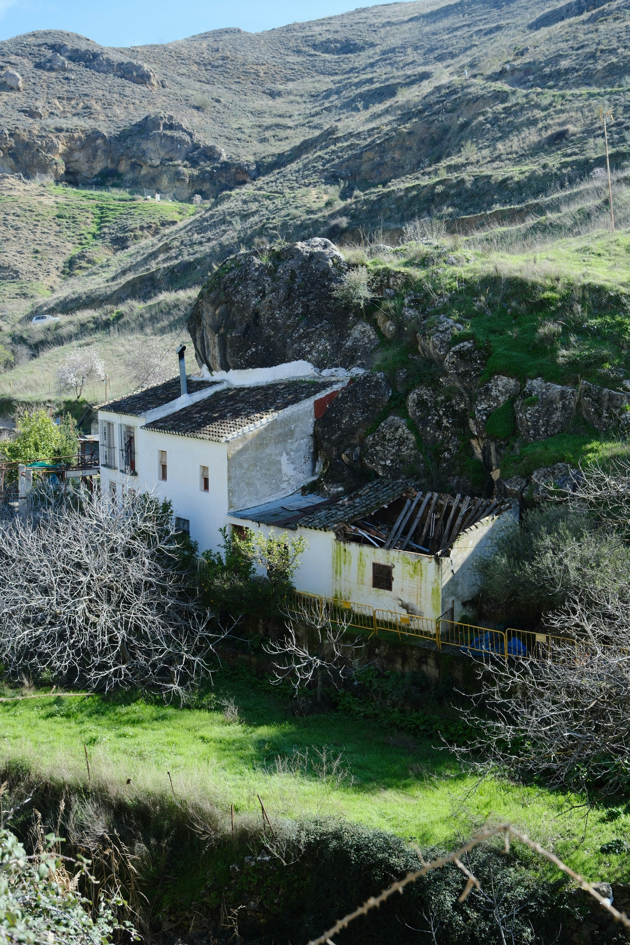 Two old houses nestled on a grassy hillside.