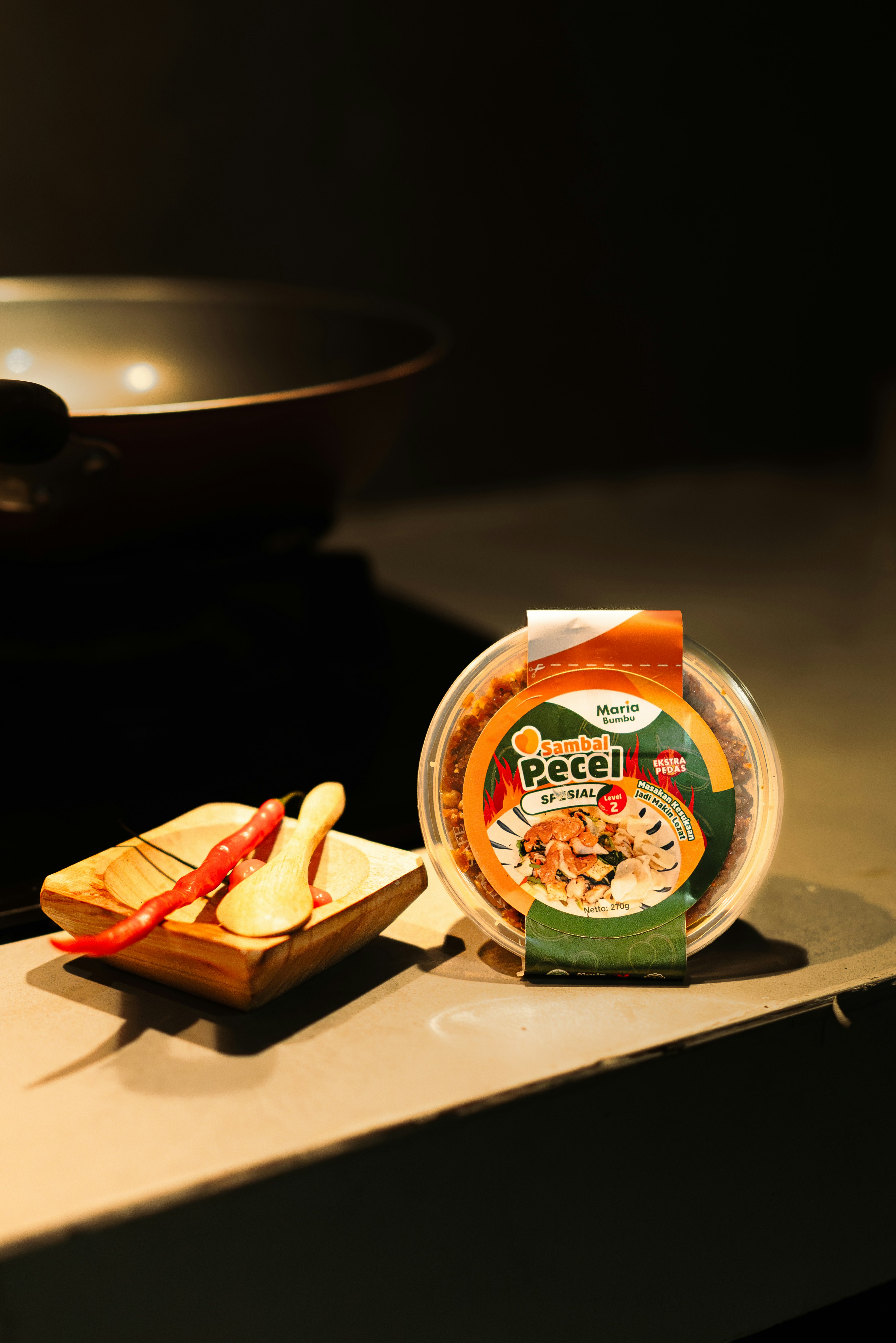 A container of pecel with chilies and spoons