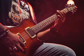 Musician playing a brown electric guitar on stage