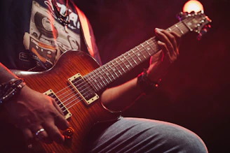 Musician playing a brown electric guitar on stage