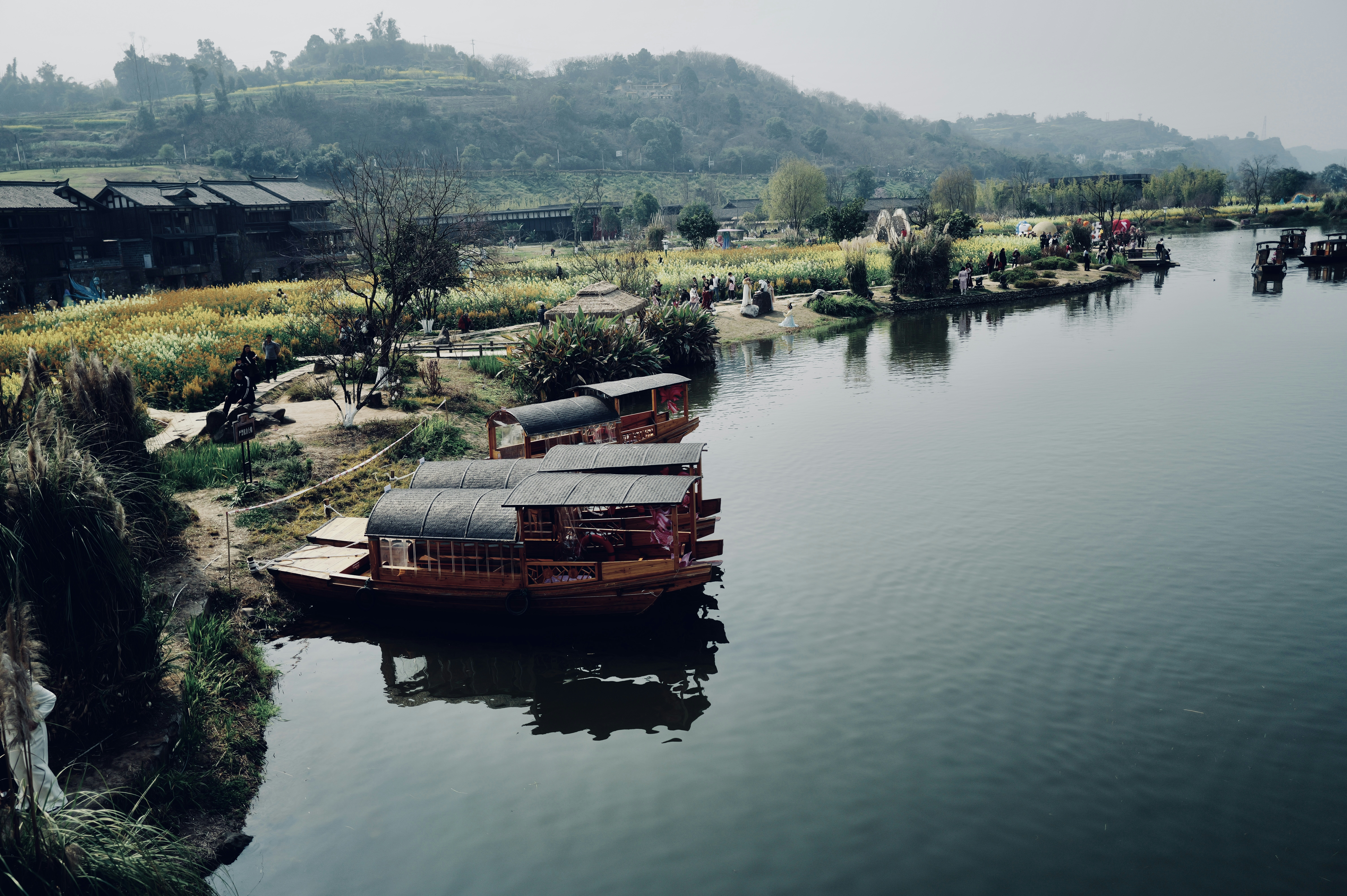 Boats docked along a serene river with lush green hills.