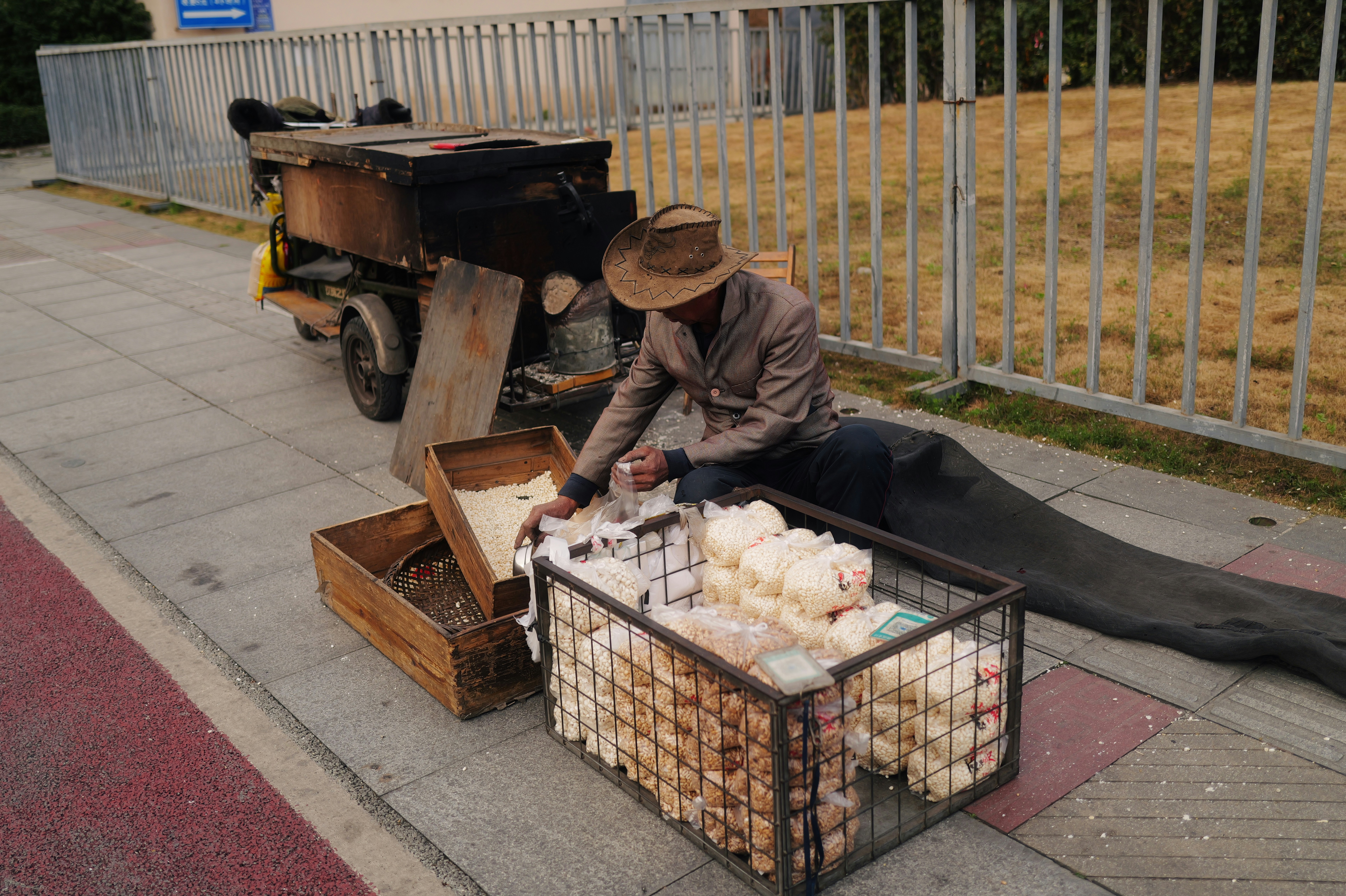 Man selling baked goods from a cart on sidewalk